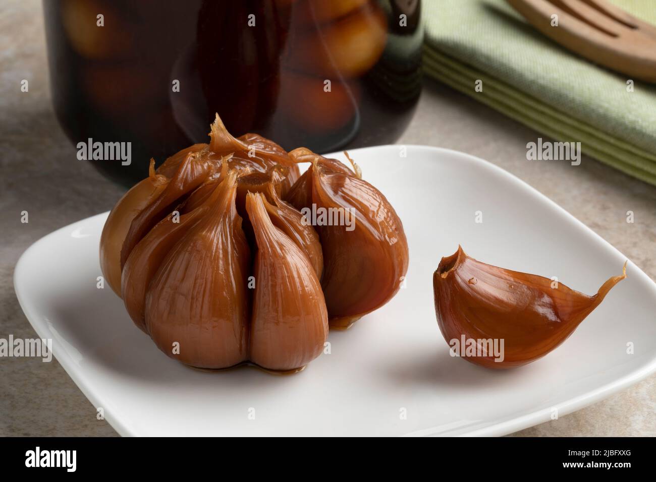 Plate with a pickled garlic bulb and a clove close up Stock Photo