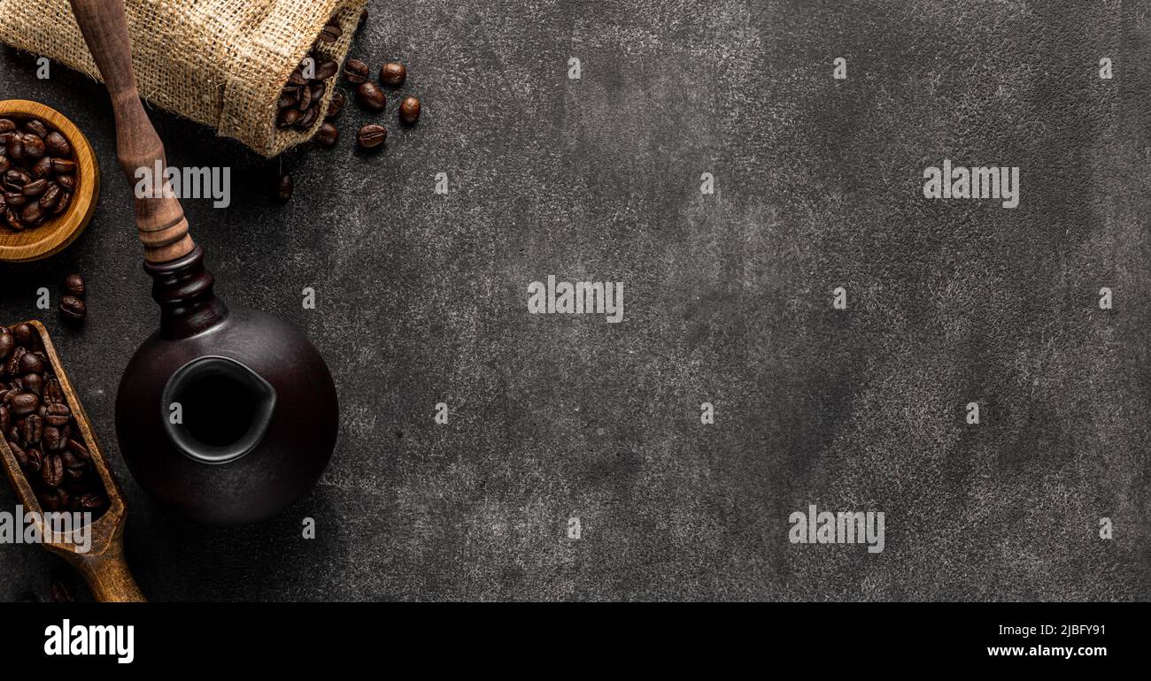 Turkish coffee background with copy space. Cezve pot, overturned bag and spatula full of roasted beans Stock Photo