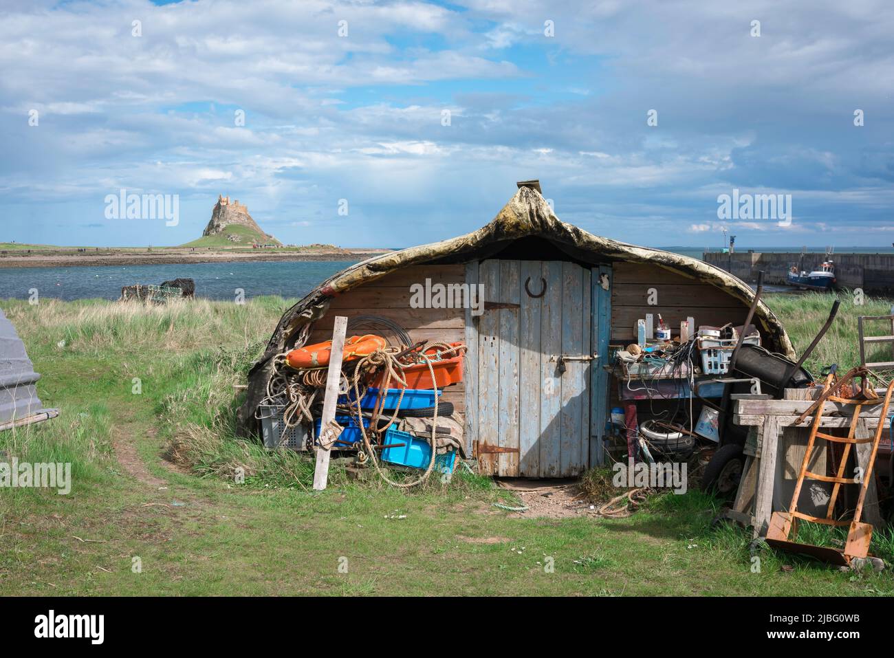 Fishing village UK, view of an upturned fishing boat serving as a storage hut in Lindisfarne harbour on the Northumberland coast, England, UK Stock Photo