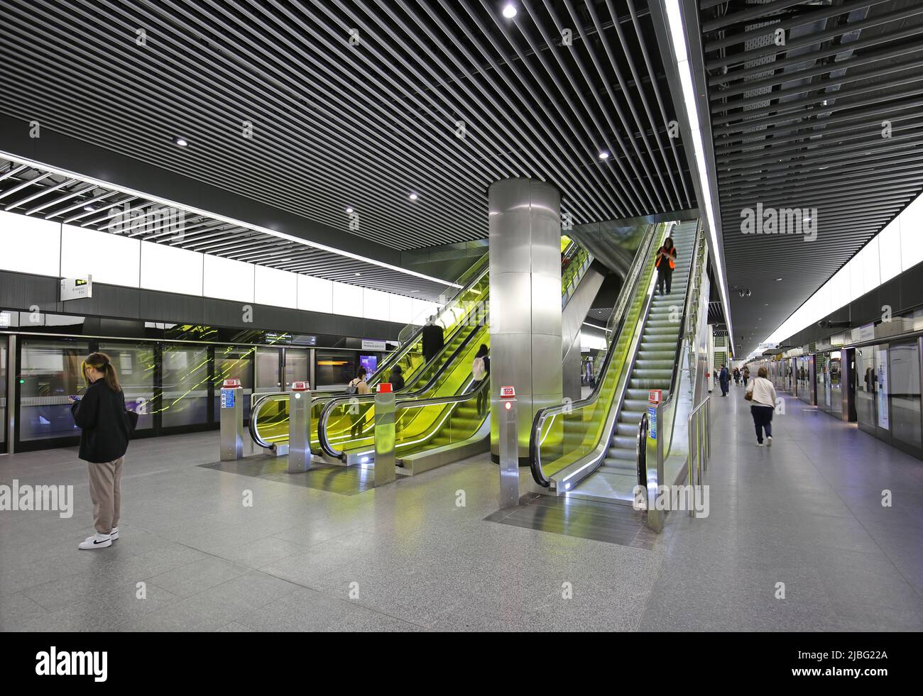 London, UK, new Elizabeth Line (Crossrail) station at Canary Wharf. Platform level view showing safety screens, passengers & escalator to ticket hall. Stock Photo