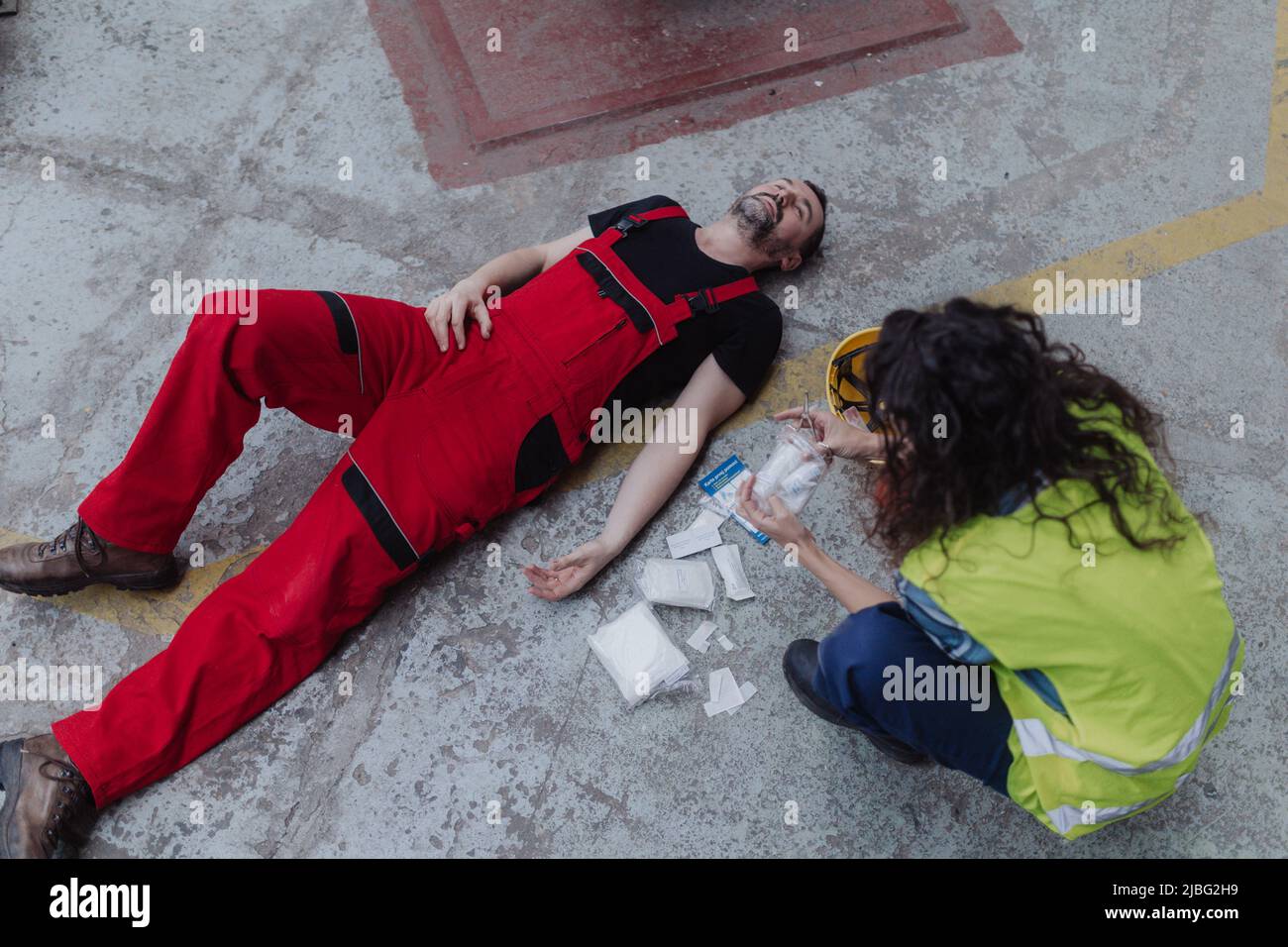 Woman is helping her colleague after accident in factory. First aid support on workplace concept. Stock Photo