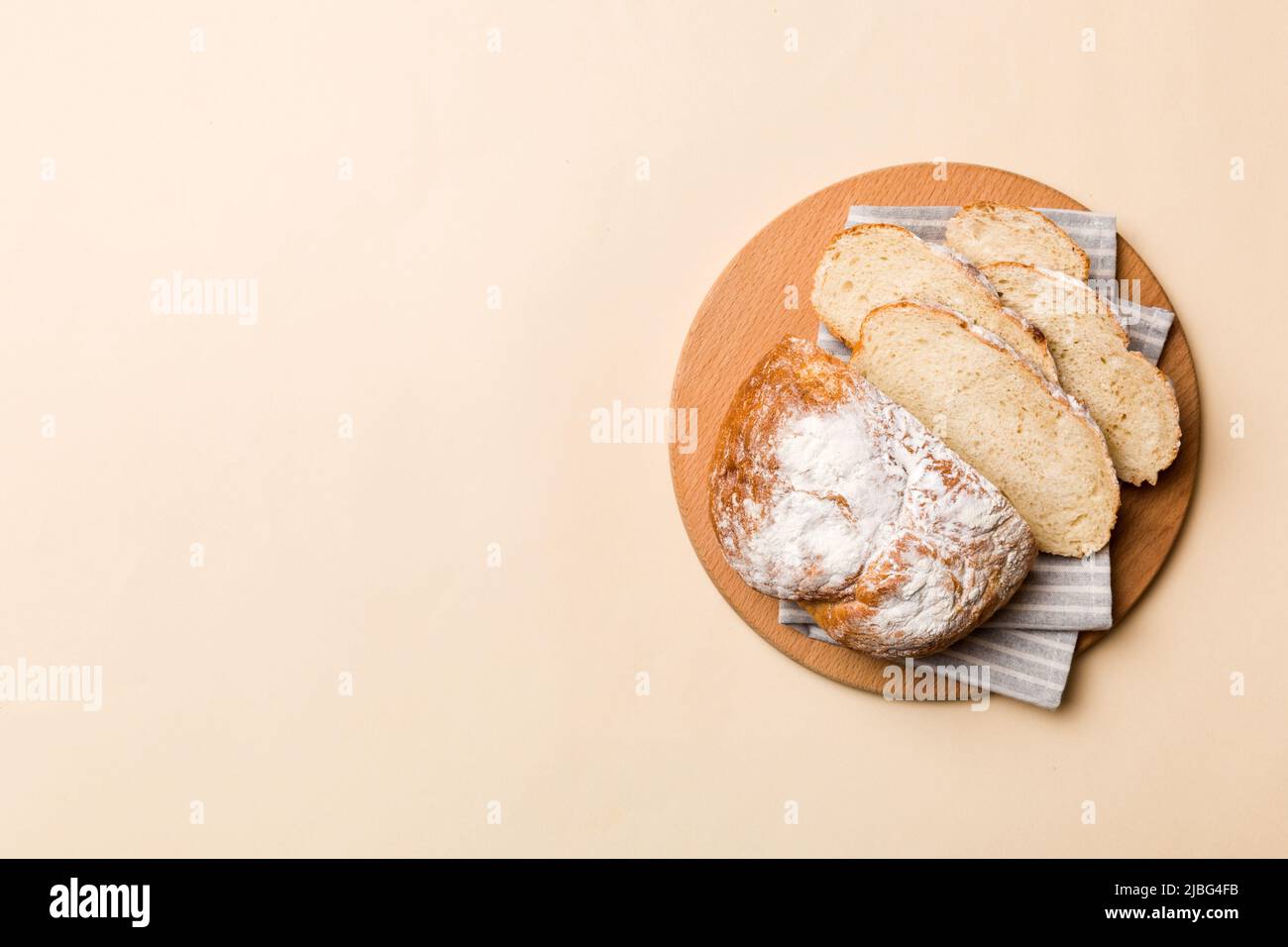 Freshly baked bread slices on cutting board against white wooden ...