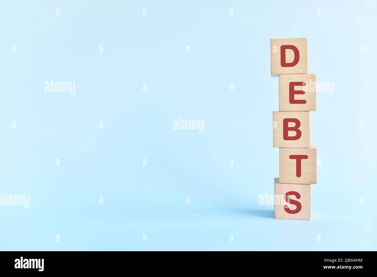 Human hand stacking word debts in wooden blocks. Growing financial debt