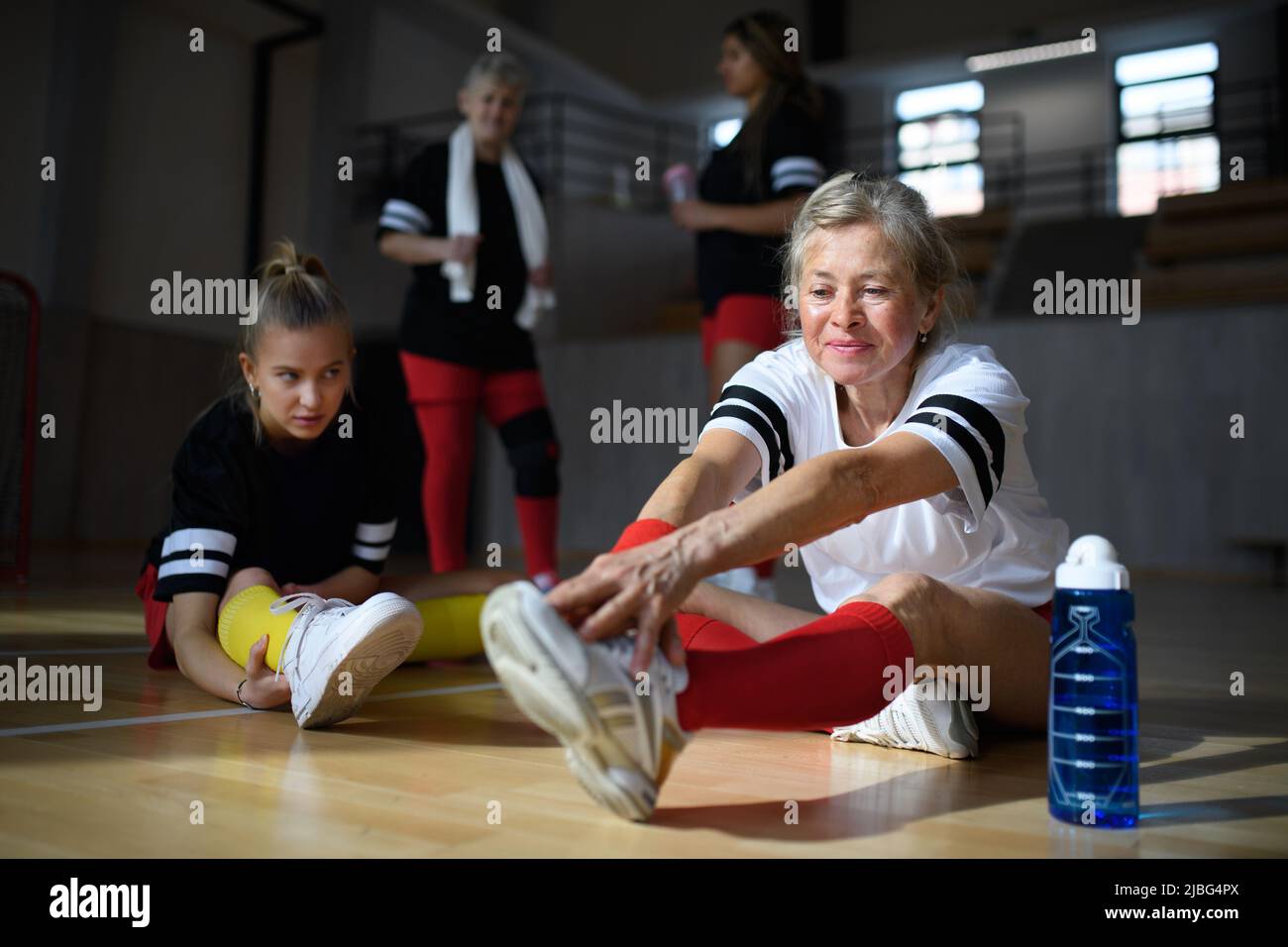 Group of young and old women, sports team players. in gym stretching