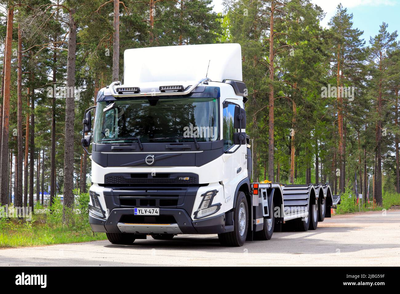 New, white Volvo FMX truck in front of forest vehicle transport trailer parked on asphalt yard. Raasepori, Finland. May 26, 2022. Stock Photo