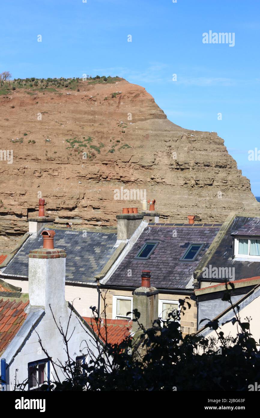A view across the rooftops of the fishing town of Staithes, Yorkshire, to the cliff tops enclosing the town Stock Photo