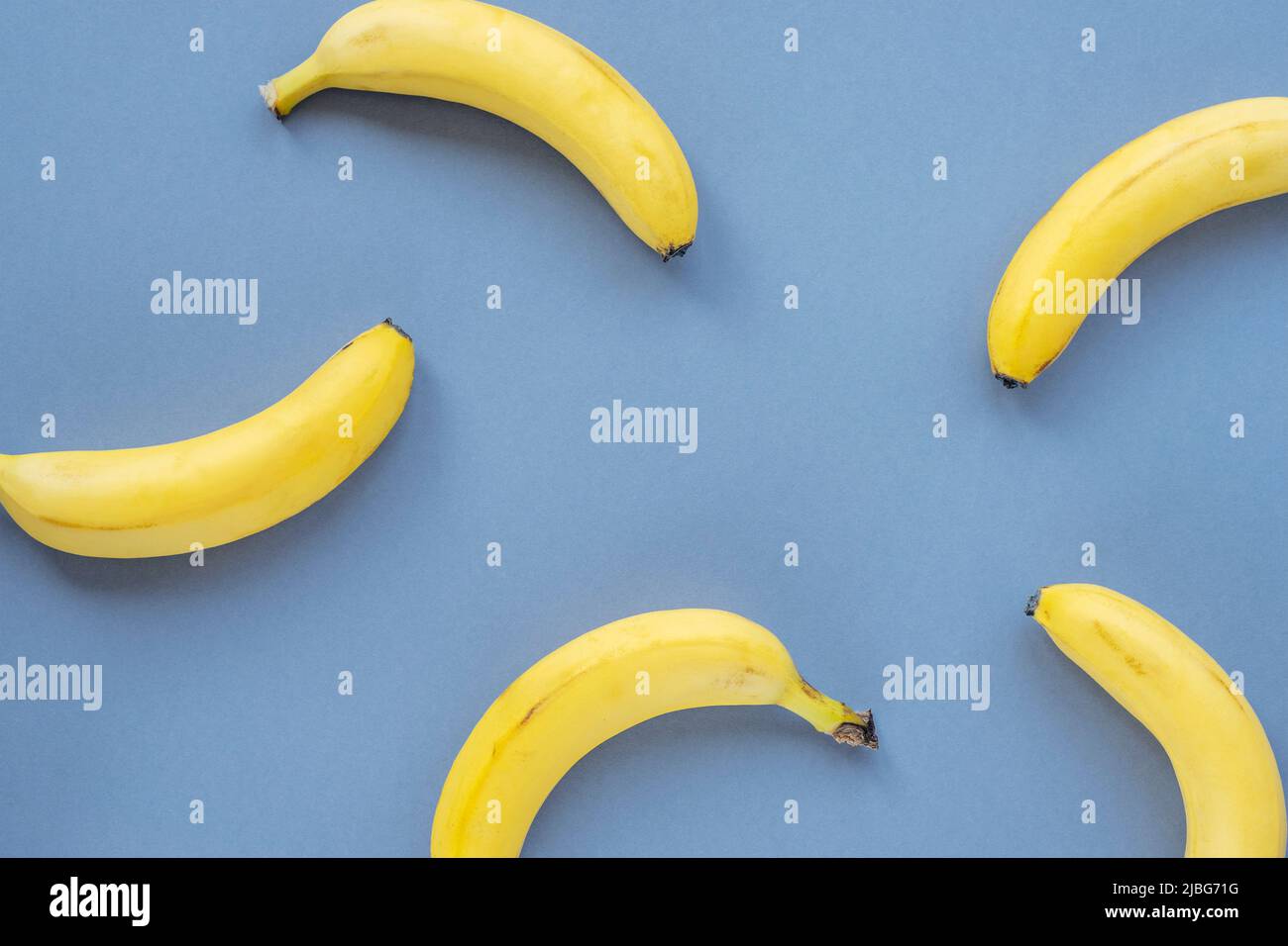 Ripe yellow bananas on blue background, texture. Stock Photo