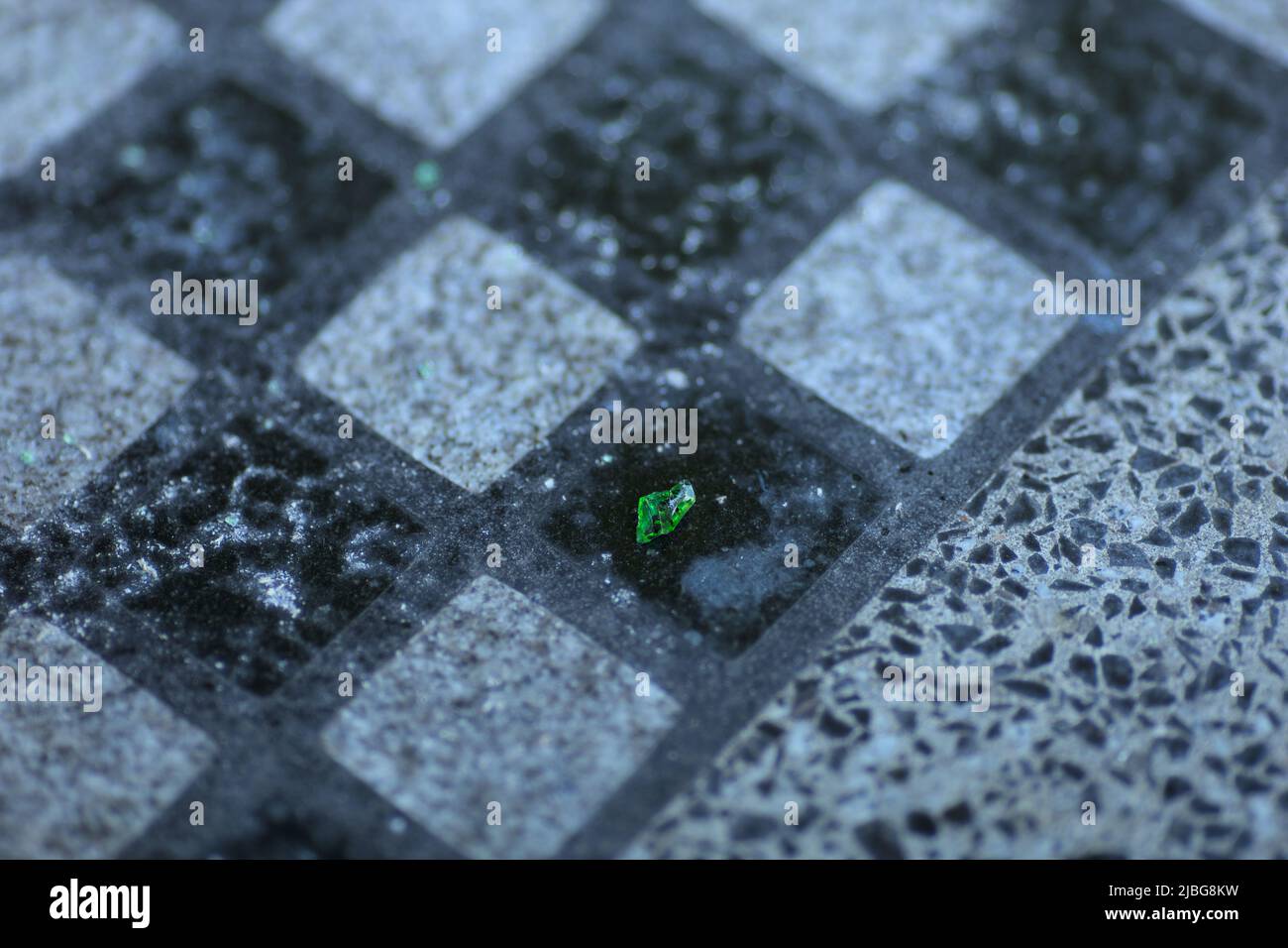 A piece of green glass on a granite chessboard in a park Stock Photo
