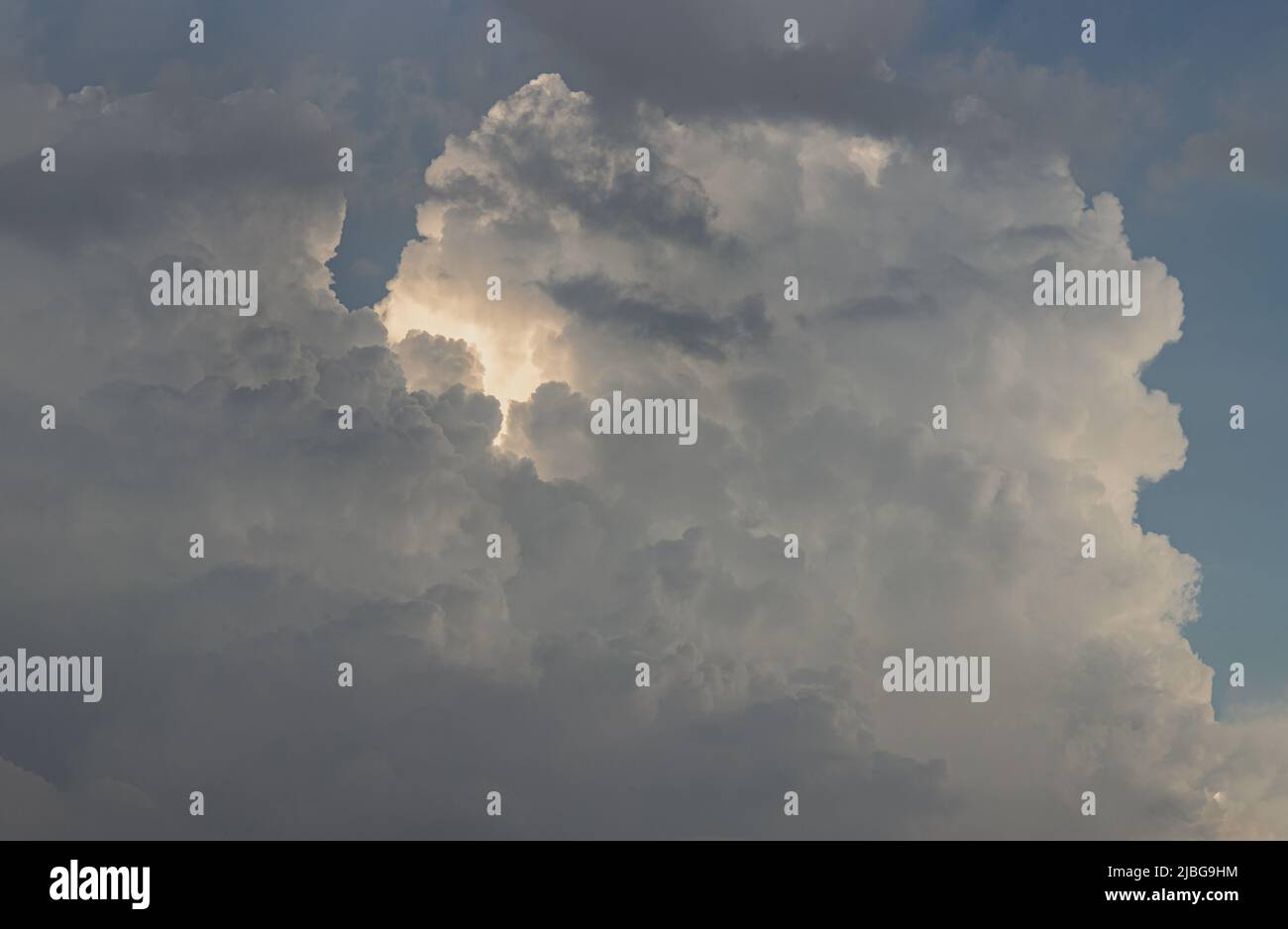 The sun shines through the clouds in the afternoon sky with dramatic ...