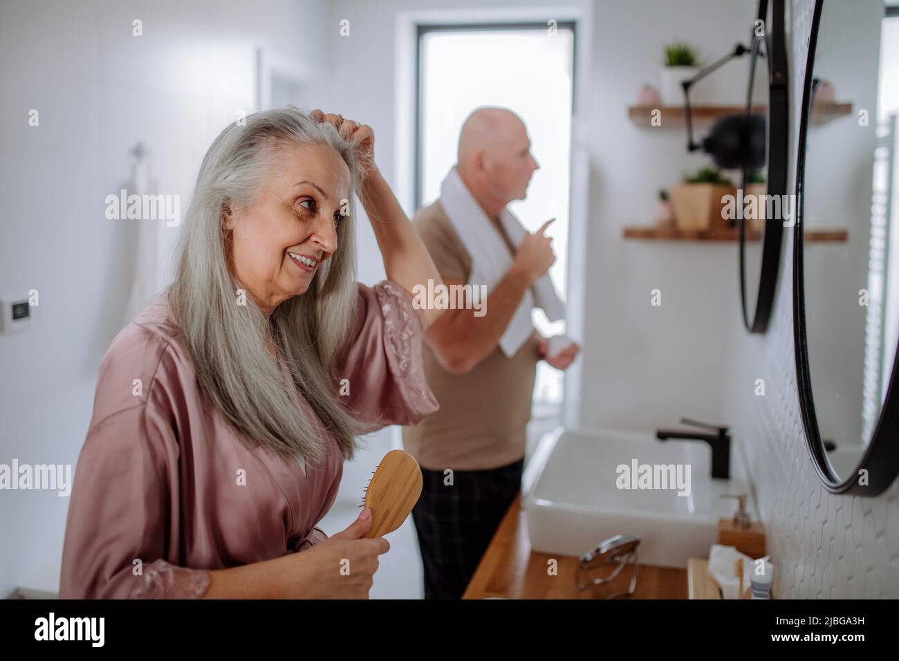 Senior couple in bathroom, brushing teeth and washing, morning routine concept. Stock Photo