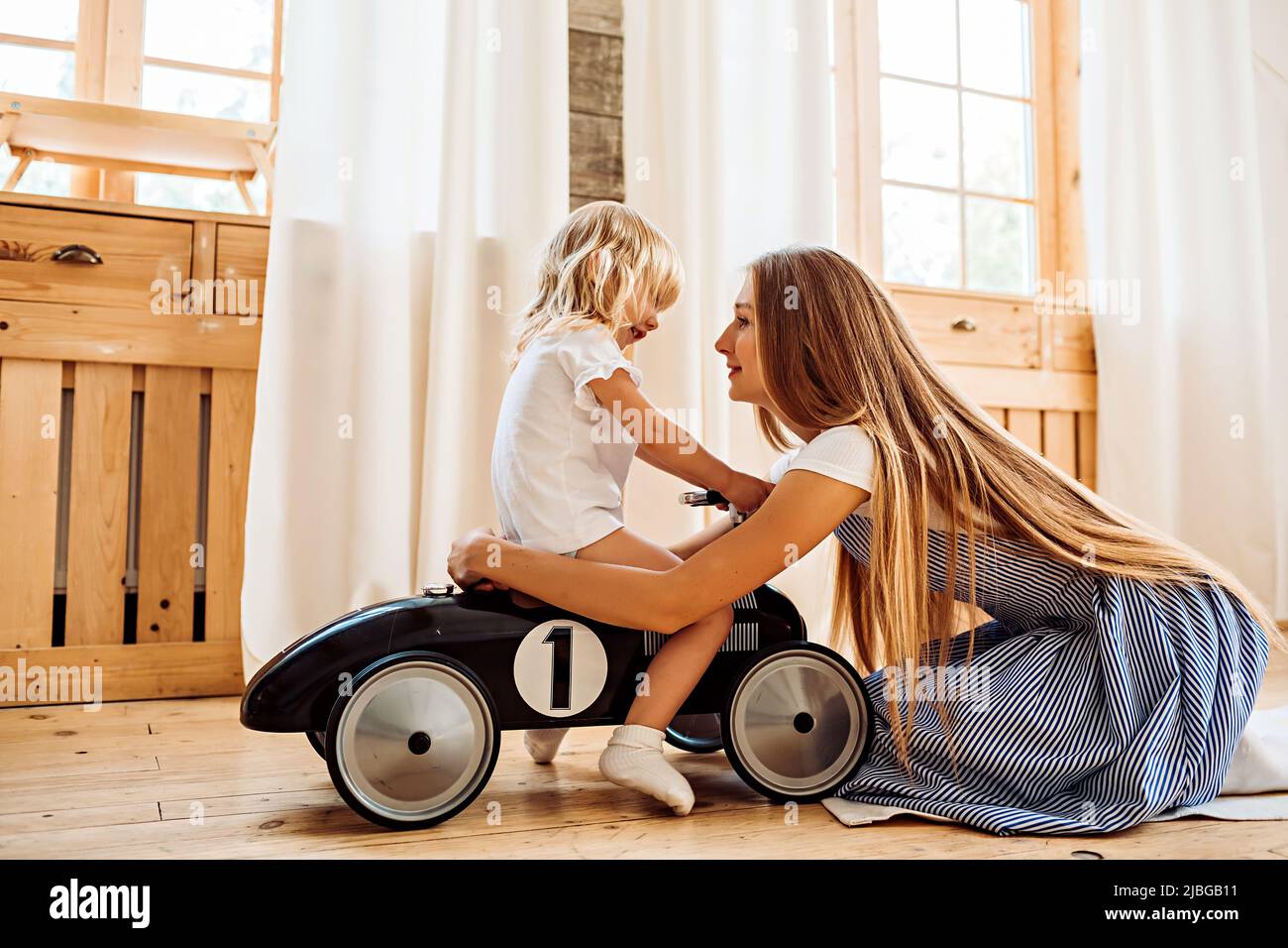 A young mother hugs her little daughter while playing at home. Family leisure lifestyle image Stock Photo