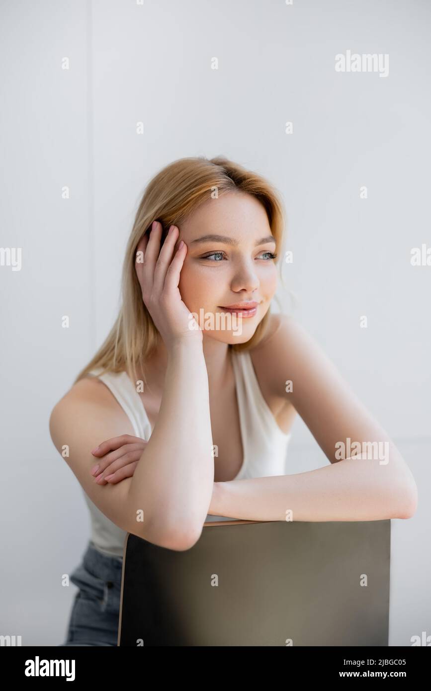 Pretty young woman sitting on chair and smiling at home Stock Photo - Alamy