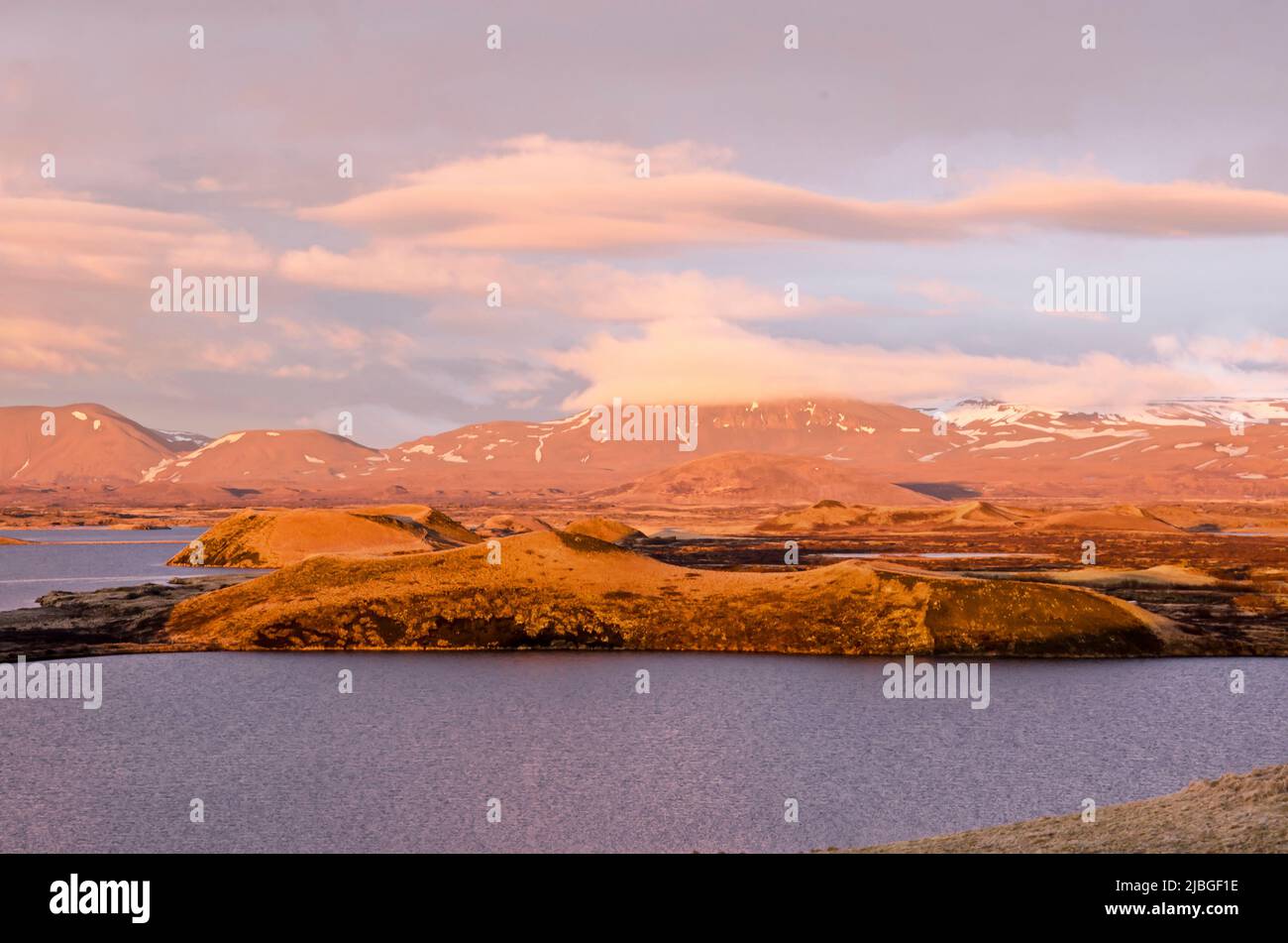 Skútustaðir, Iceland, April 27, 2022: Clouds, pseudocraters and lake Myvatn, put in a warm light by the setting sun during the golden hour Stock Photo