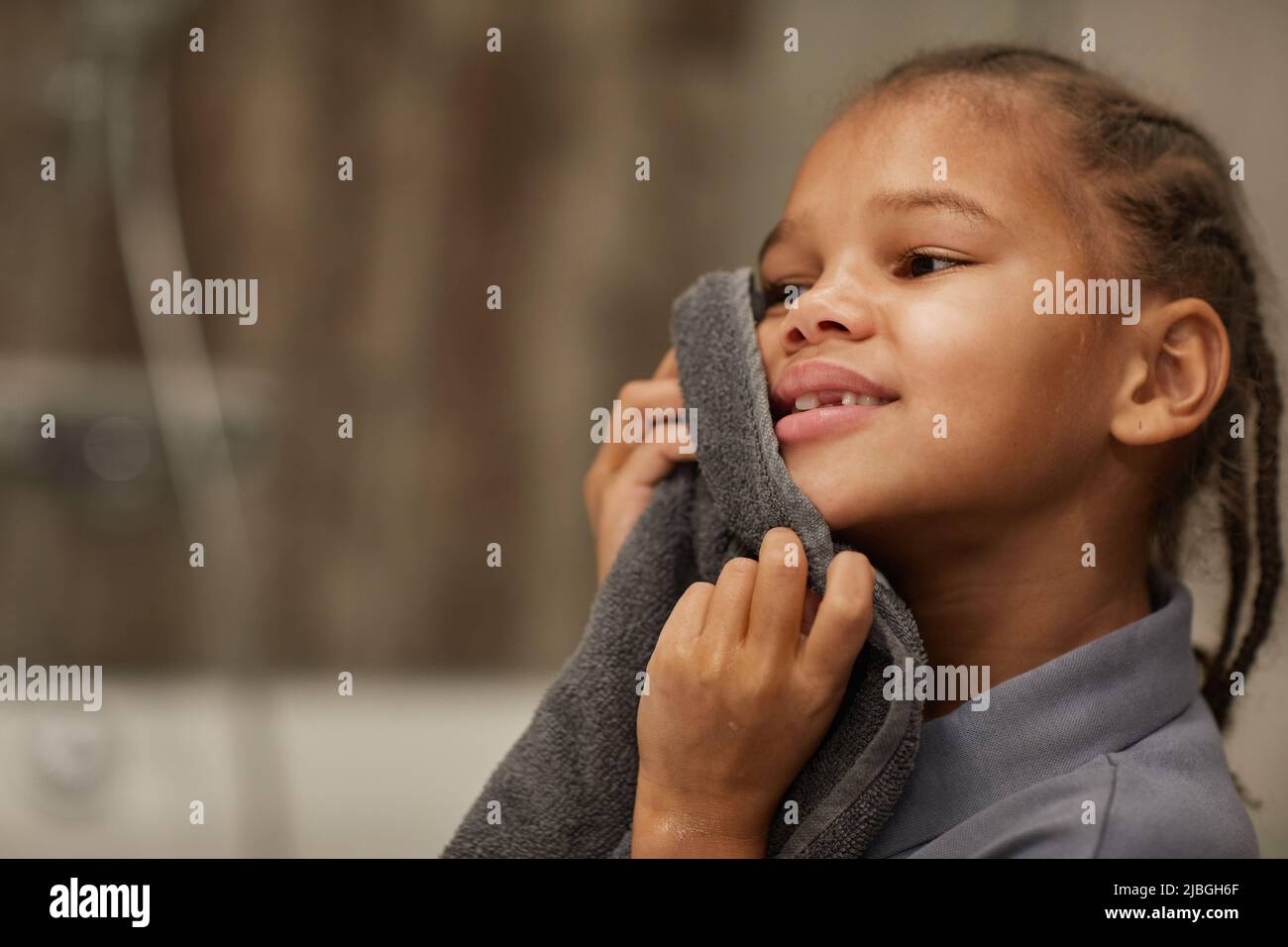 Close up of little black girl washing face in bathroom and holding