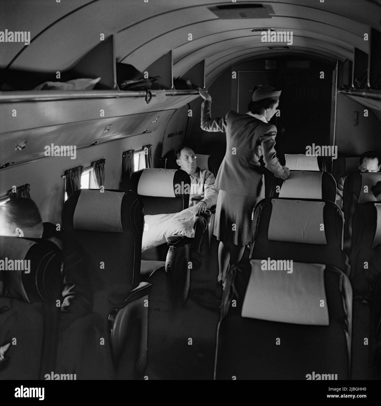 Vintage photo circa 1941 of a flight attendant looking after passengers travelling in a Douglas DC3 airliner operated by United Airlines flying from Los Angeles to San Francisco Stock Photo