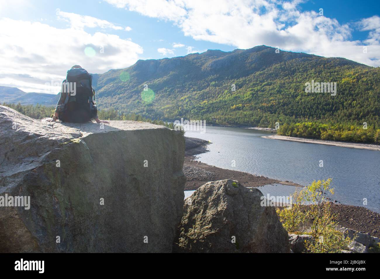 Female backpacker in Stavanger Norway with sun burst and summer fjord