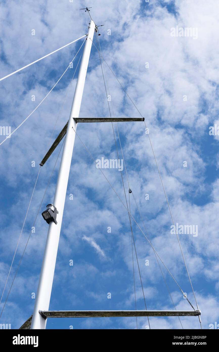 Mast and rigging of a modern sailing ship against a blue sky with small ...