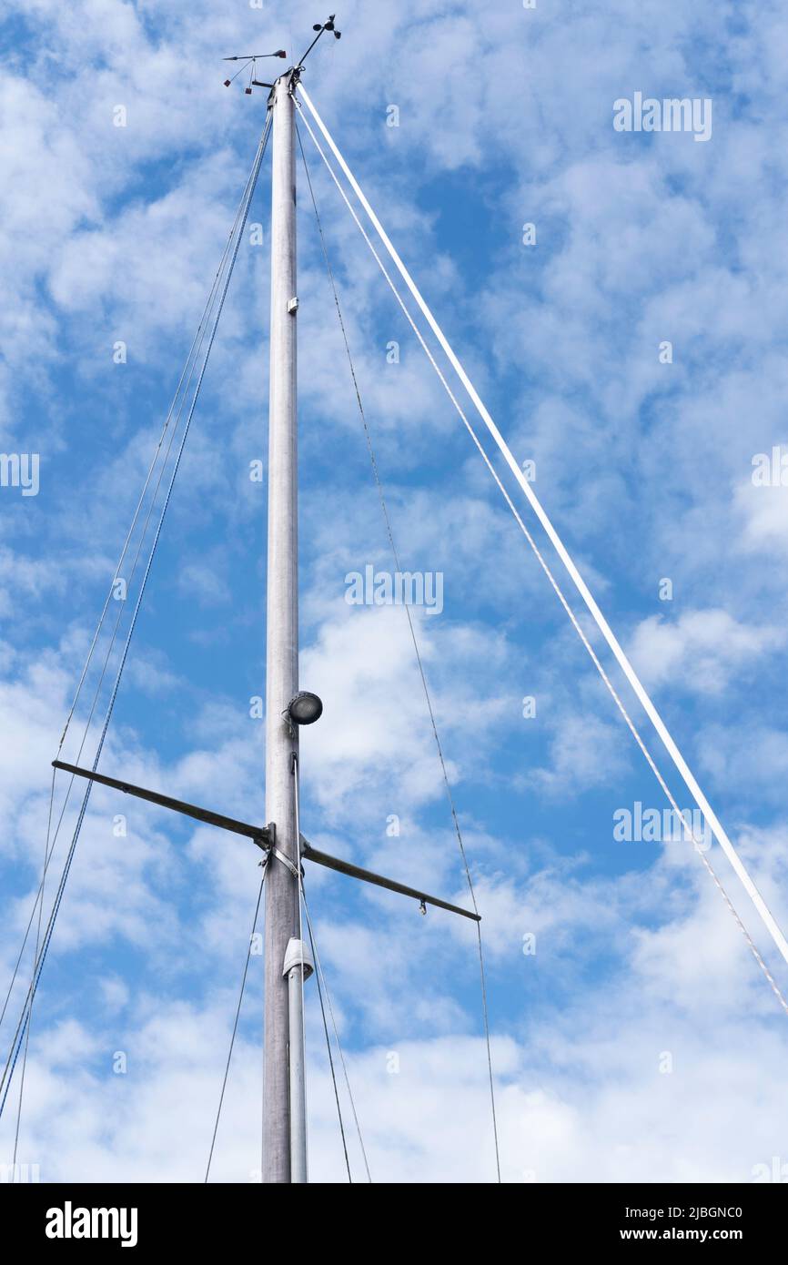 Mast and rigging of a modern sailing ship against a blue sky with small ...