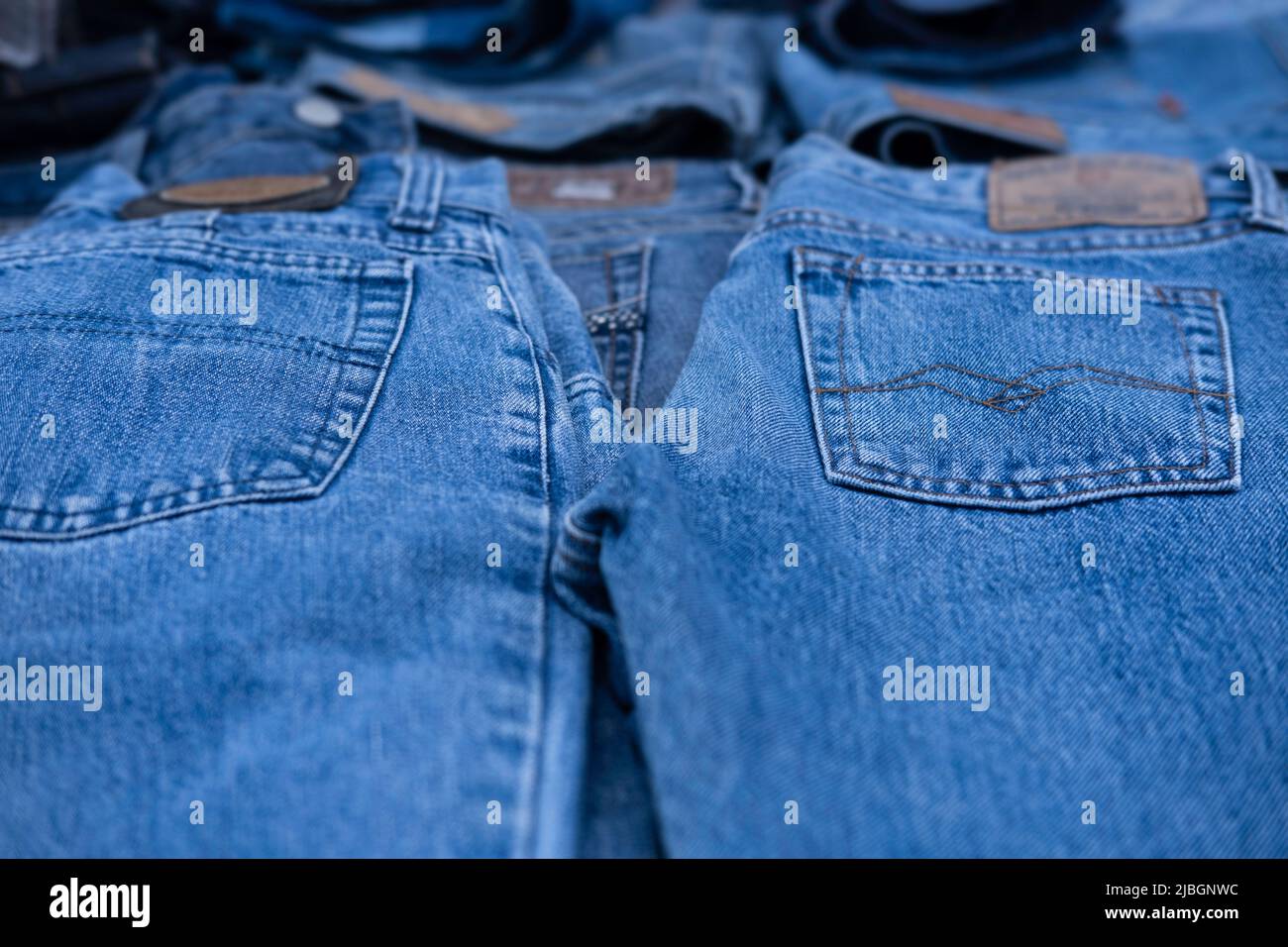 Jeans are displayed in a market stall. Focus on the pockets on the pants, the brands are blurred. Background image Stock Photo