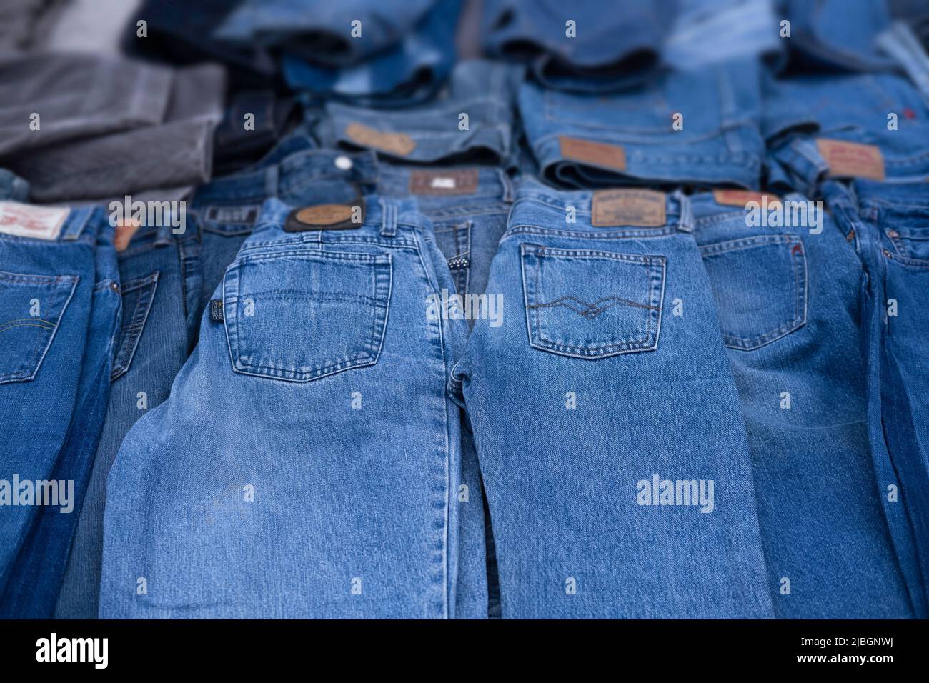 Jeans are displayed in a market stall. Focus on the pockets on the pants, the brands are blurred. Background image Stock Photo