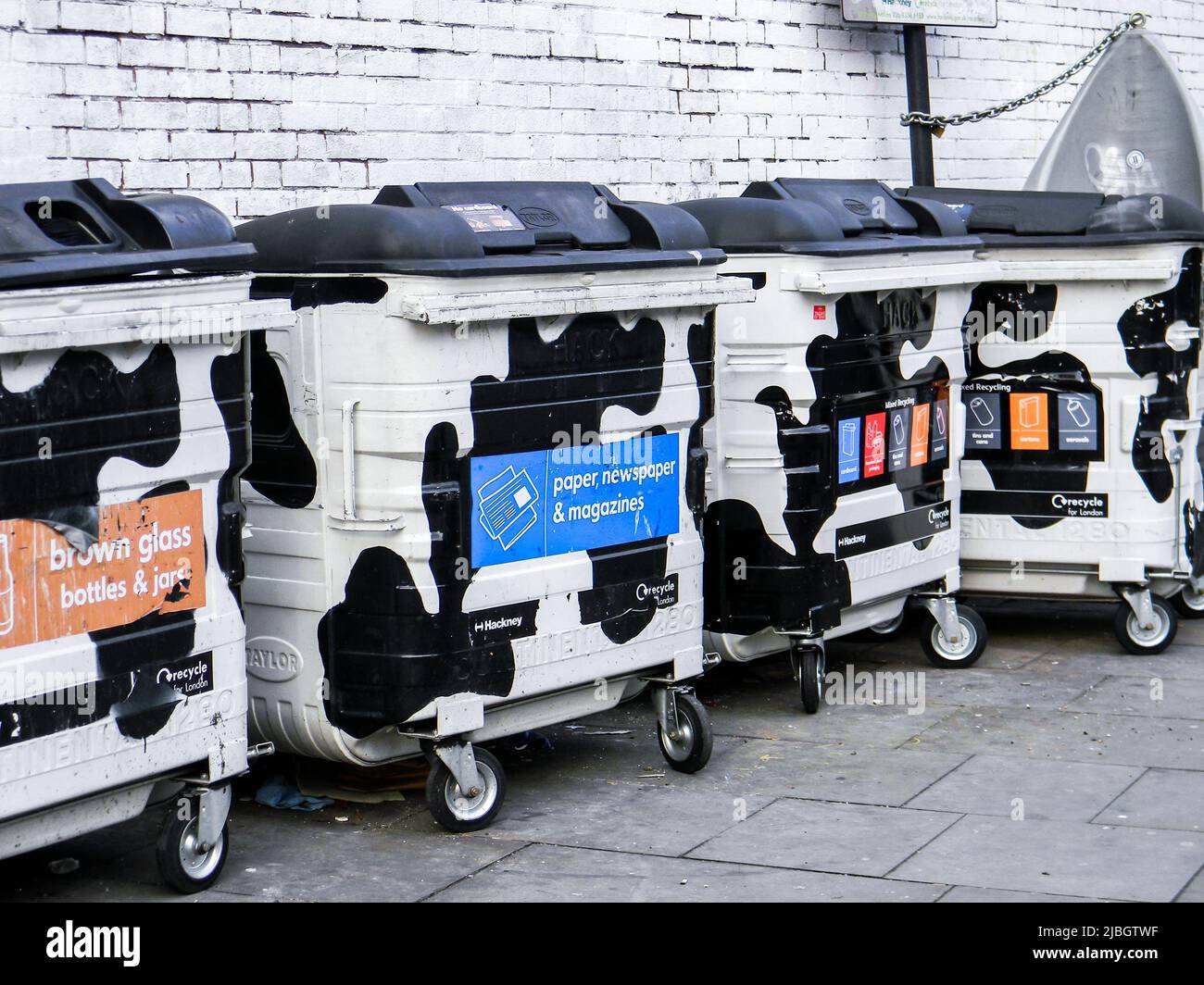 Dustbins with wheels & milk cow patterned design by Taylor on street. Bins colourfully labeled by London Recycles and separated by type of garbages Stock Photo