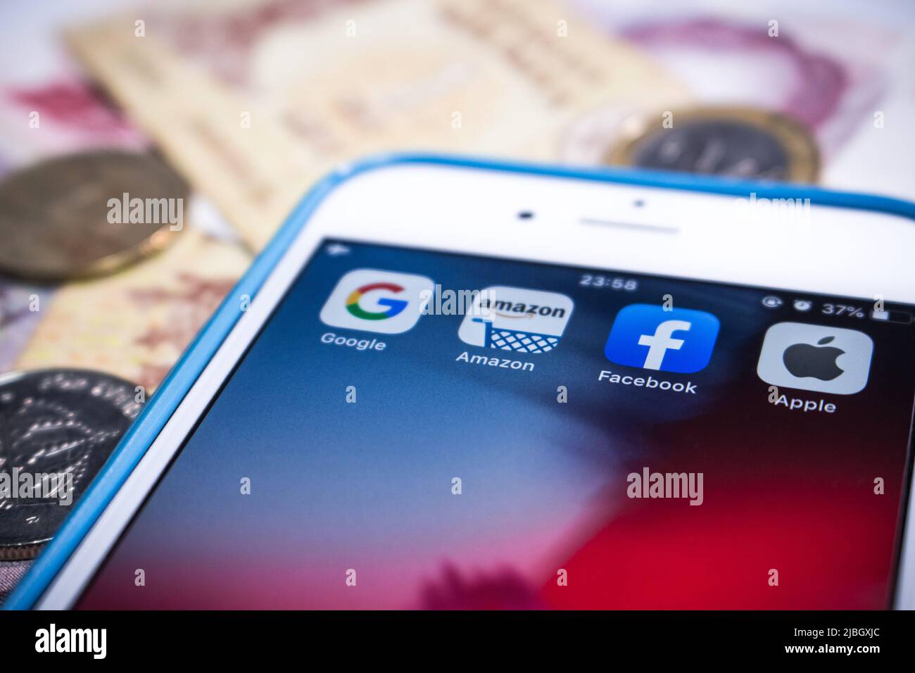 GAFA on iPhone & money (coins & bills). Google, Amazon, Facebook and Apple are the 4 US multinational companies that dominated cyberspace during 2010s Stock Photo