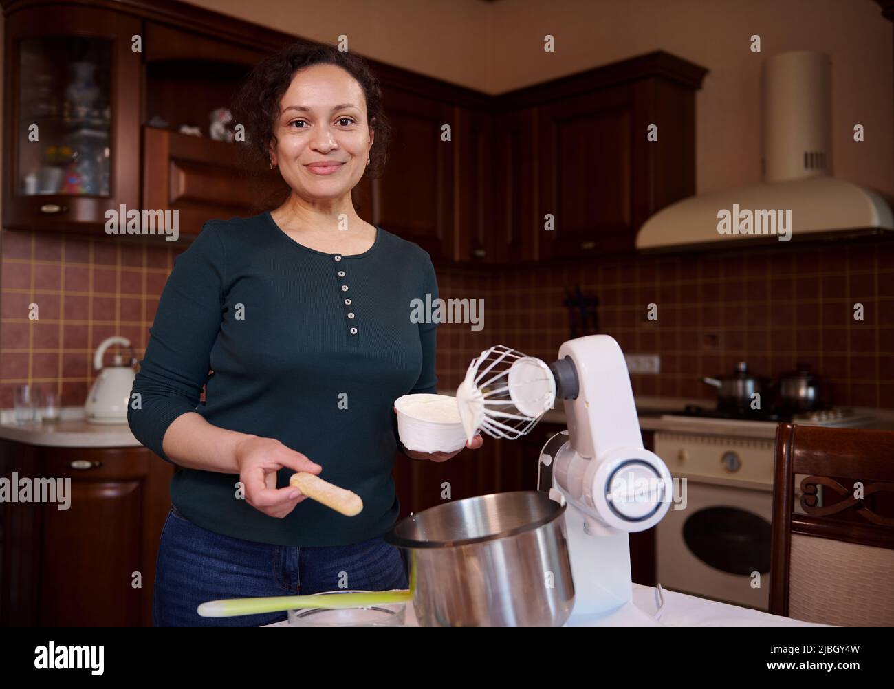 Pleasant mature woman preparing cheesecake in home kitchen. Pastry chef