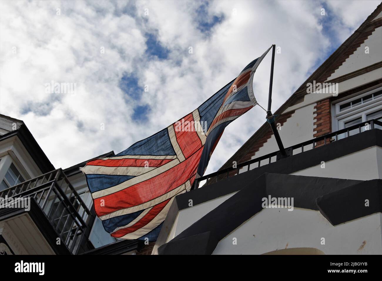 A large cloth union jack seen from below flying in the wind on a sunny day. Concept for the UK, fading strength, glory days Stock Photo