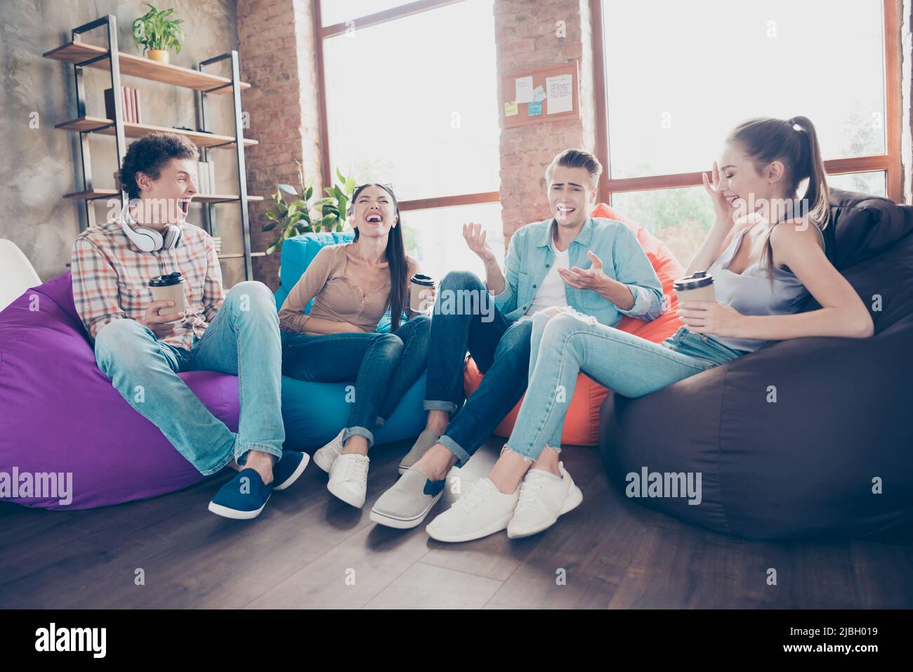 Photo of funny funky workers group sitting dorm bean bags drinking