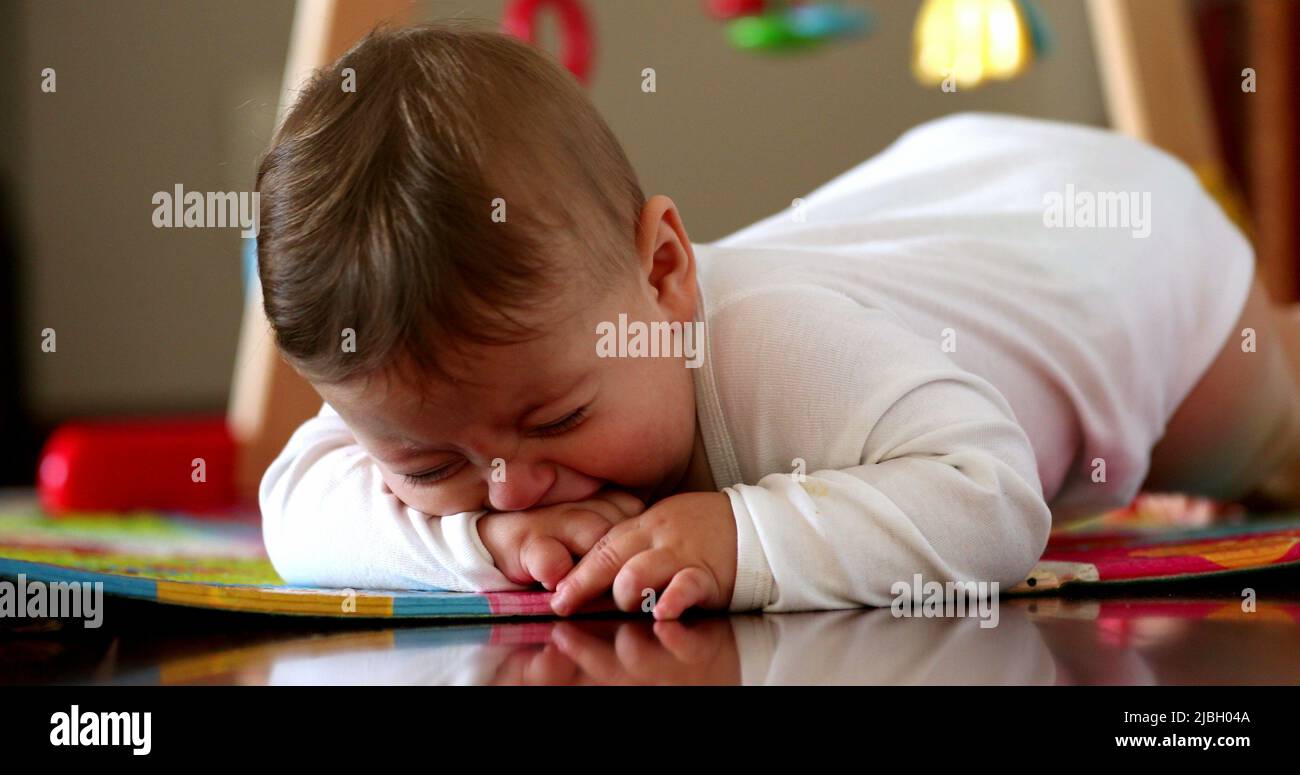 Upset baby infant crying, tired angry one year old toddler lying on