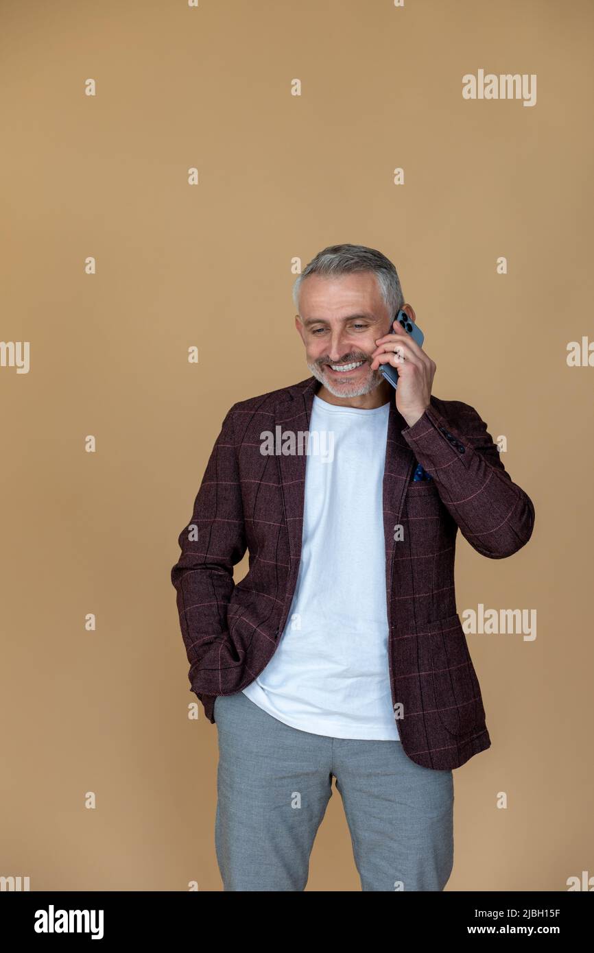 Man in a jacket talking on the phone and looking contented Stock Photo
