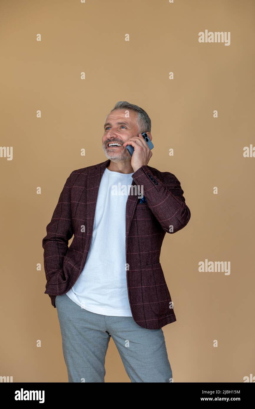 Man in a jacket talking on the phone and looking contented Stock Photo