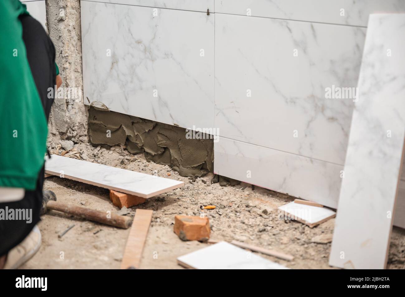 Male tiler using trowel laying marble tile with cement in bathroom. Housing development