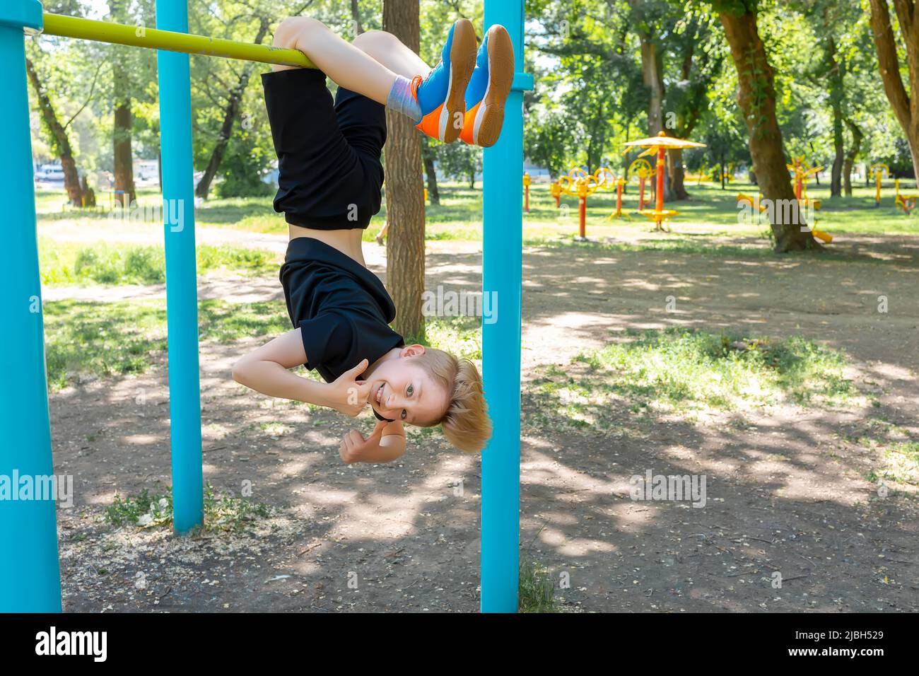 athlete boy hanging upside down and laughing showing thumb up Stock Photo
