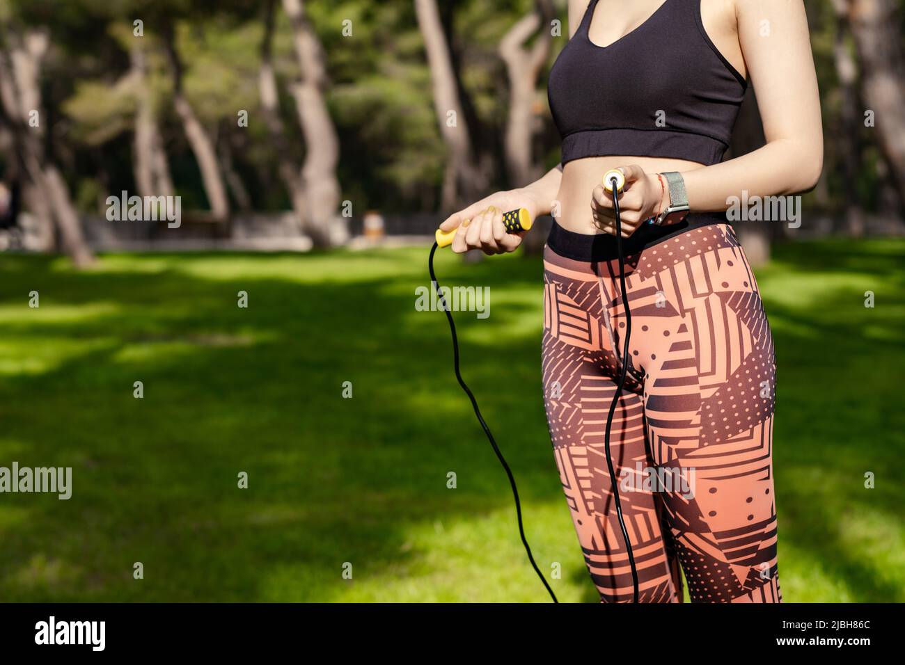 Beautiful redhead woman wearing black sports bra standing on city park,  outdoors flat stomach with a skipping rope in her hands at waist level.  Health Stock Photo - Alamy