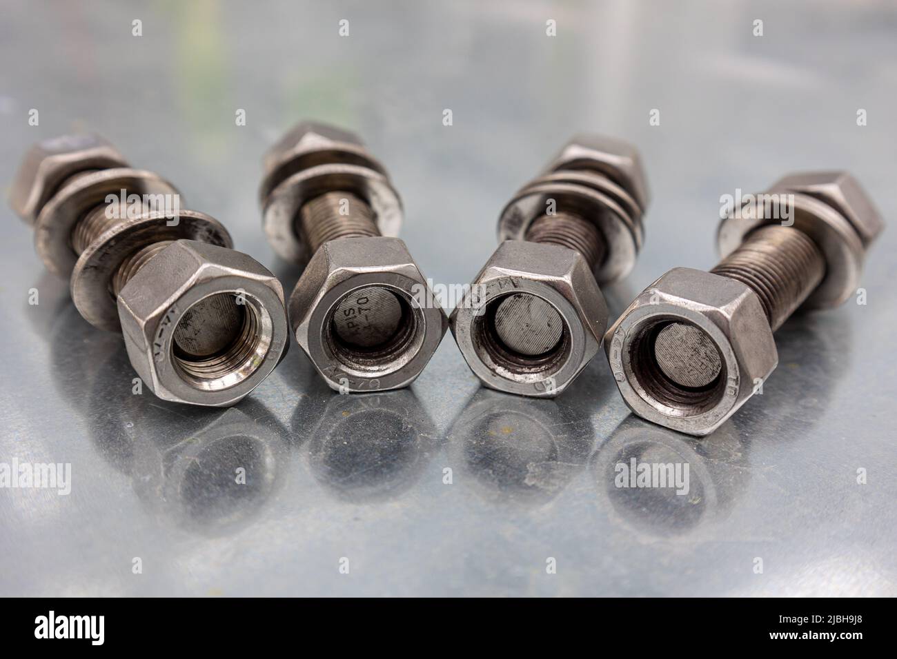 Large bolts and nuts on a galvanized sheet, ready for industrial mounting Stock Photo