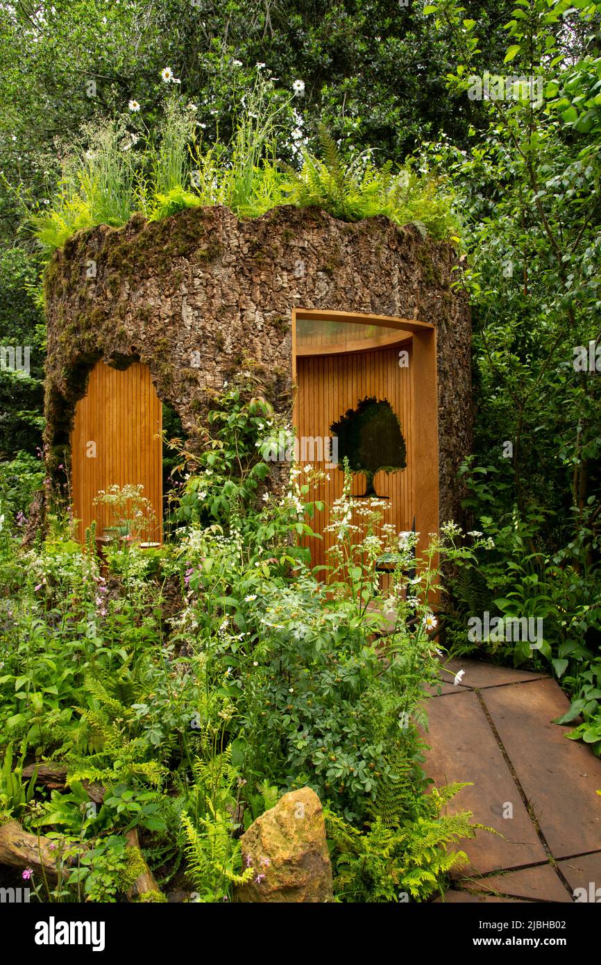 A woodland sanctury in a larger than life oak tree stump in the Connected by Exante Garden designed by Tania Suonio Stock Photo