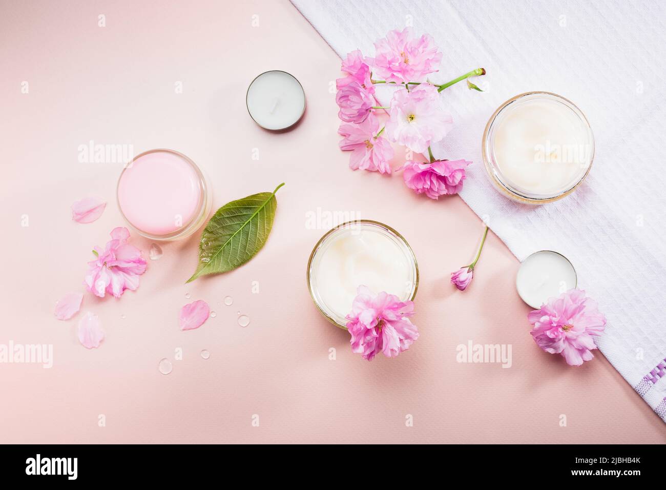 Body care cream and pink cherry blossoms. Flat lay. Stock Photo