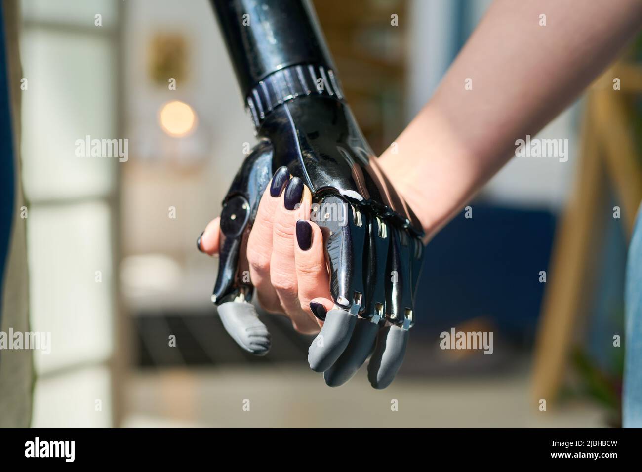 Young woman with black nail polish on her fingernails holding by myoelectric hand belonging to person with physical disability Stock Photo