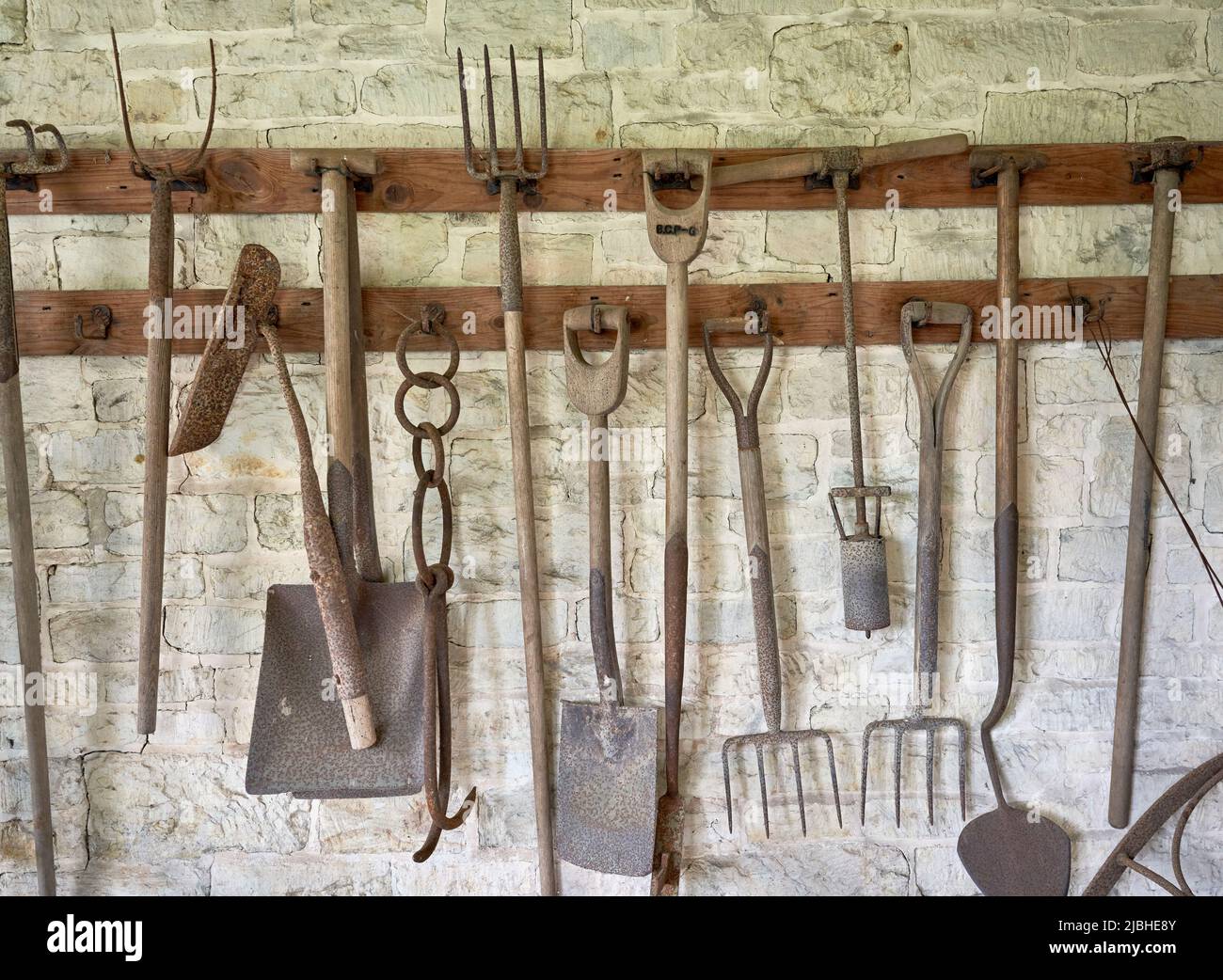 Vintage garden tools hanging on a whitewashed wall Stock Photo