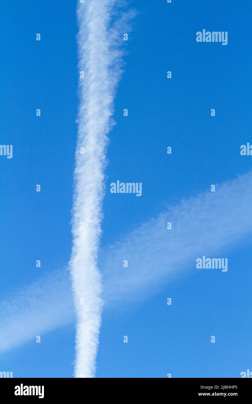 Contrails crossing in a bright blue sky. Stock Photo