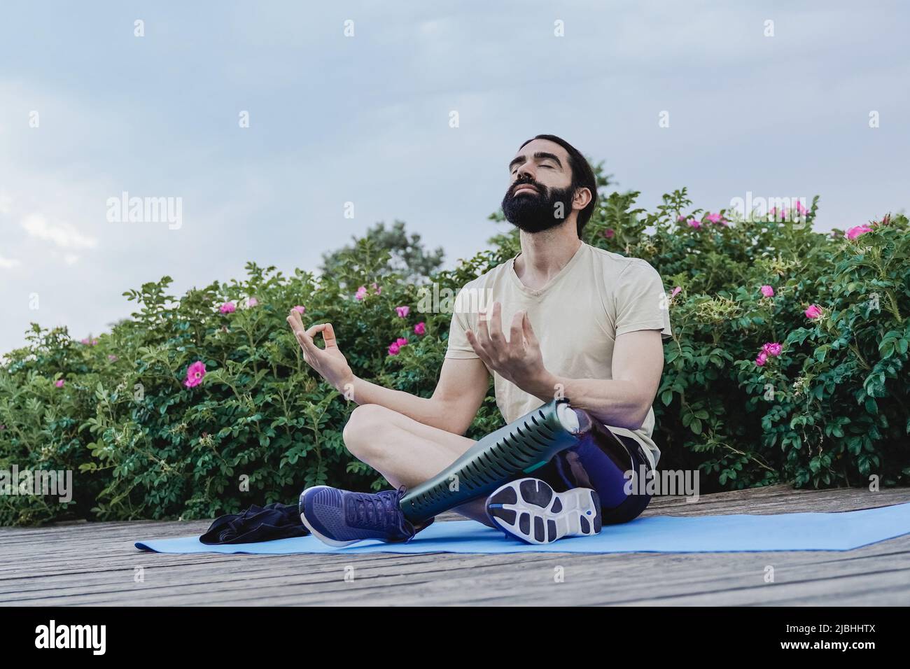 Young man with prosthetic leg doing meditation outdoor at city park - Focus on face Stock Photo