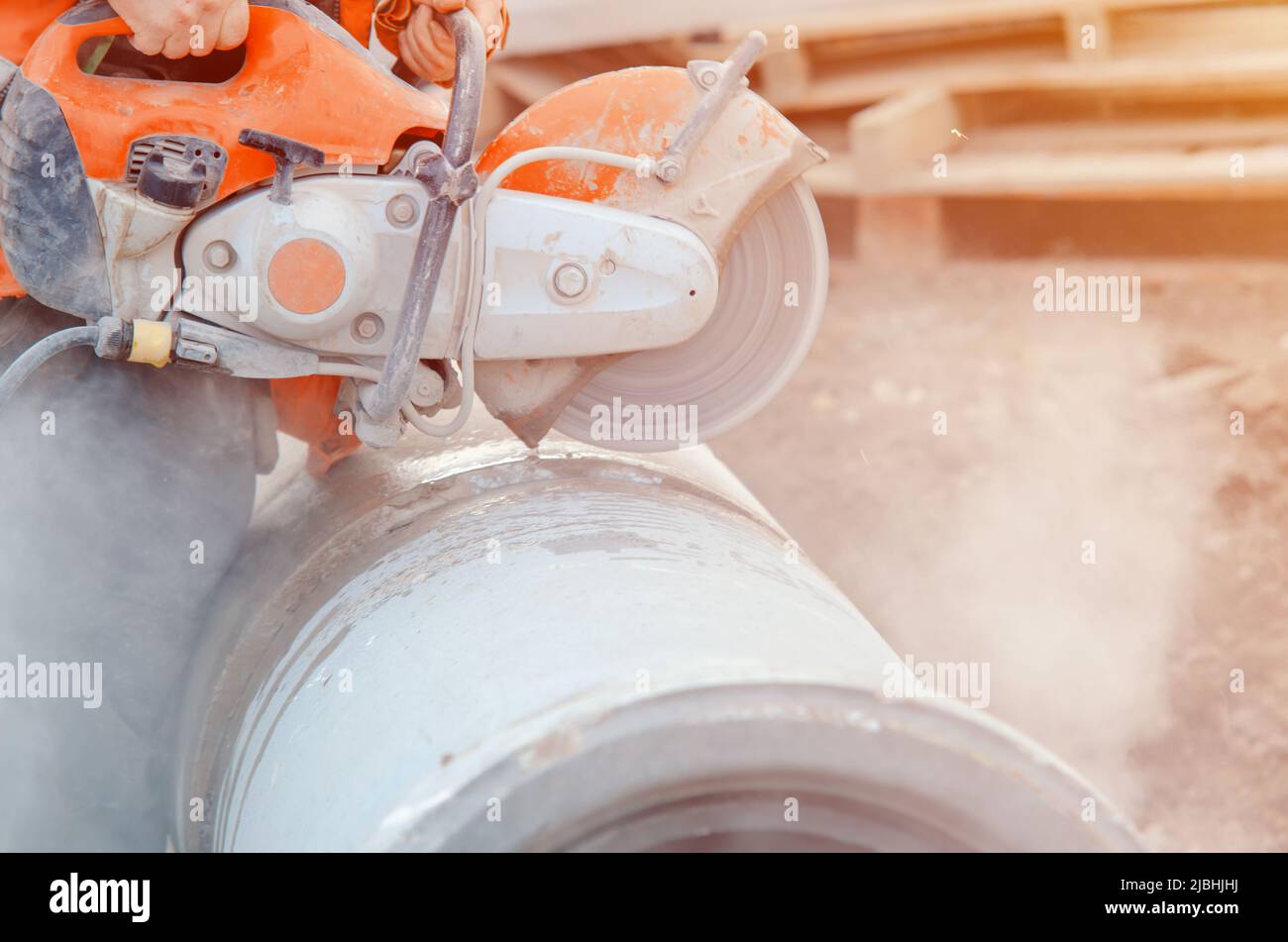 A worker at the construction site cutting a concrete drainage pipe with