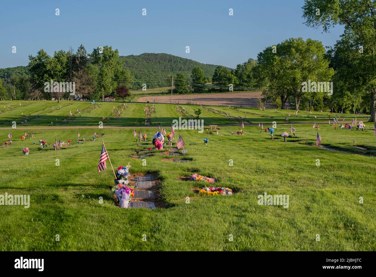 A man tends to a grave at a cemetery in rural Pennsylvania on Memorial Day. - Stock Image