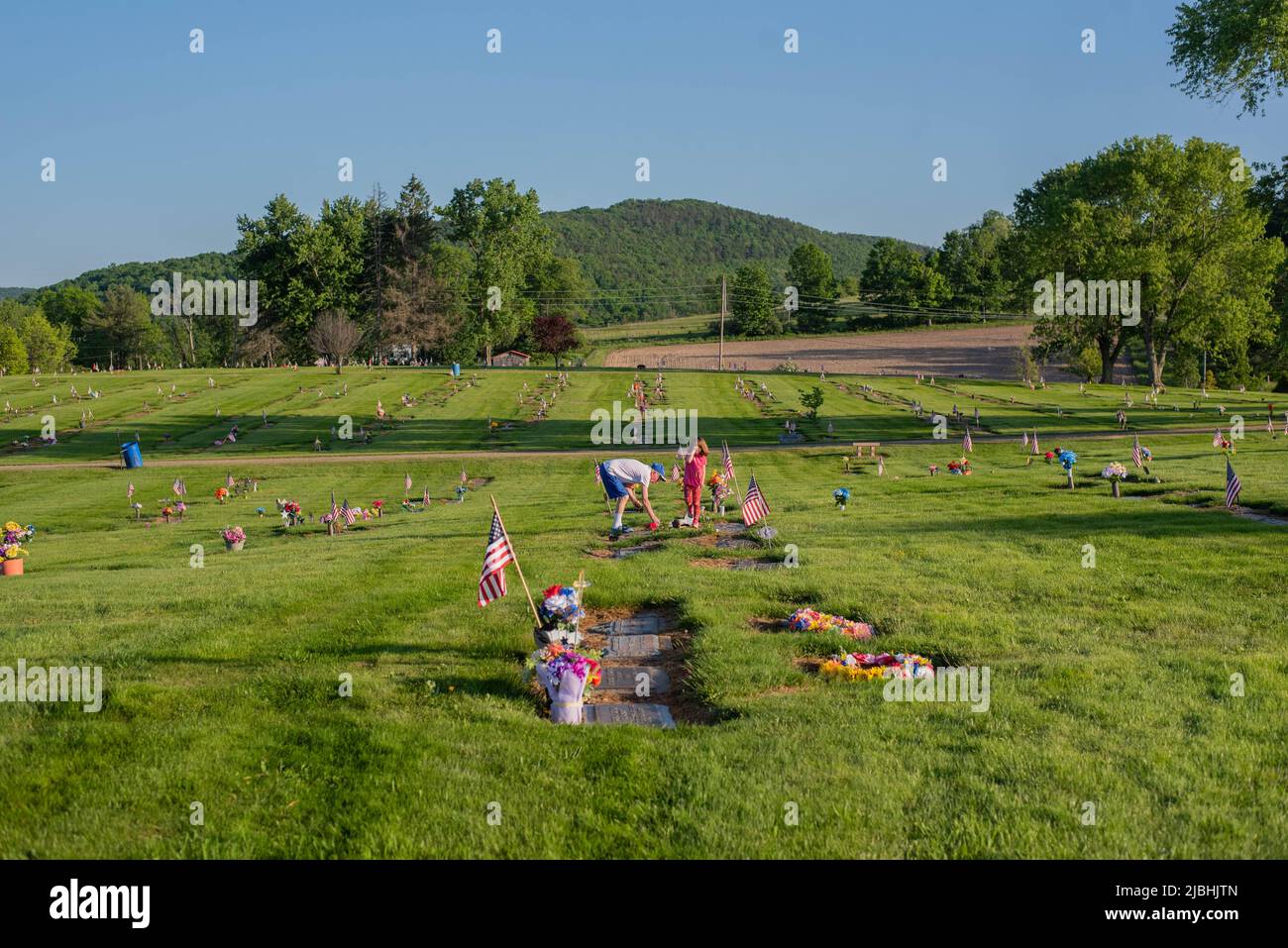 A man tends to a grave at a cemetery in rural Pennsylvania on Memorial Day. - Stock Image