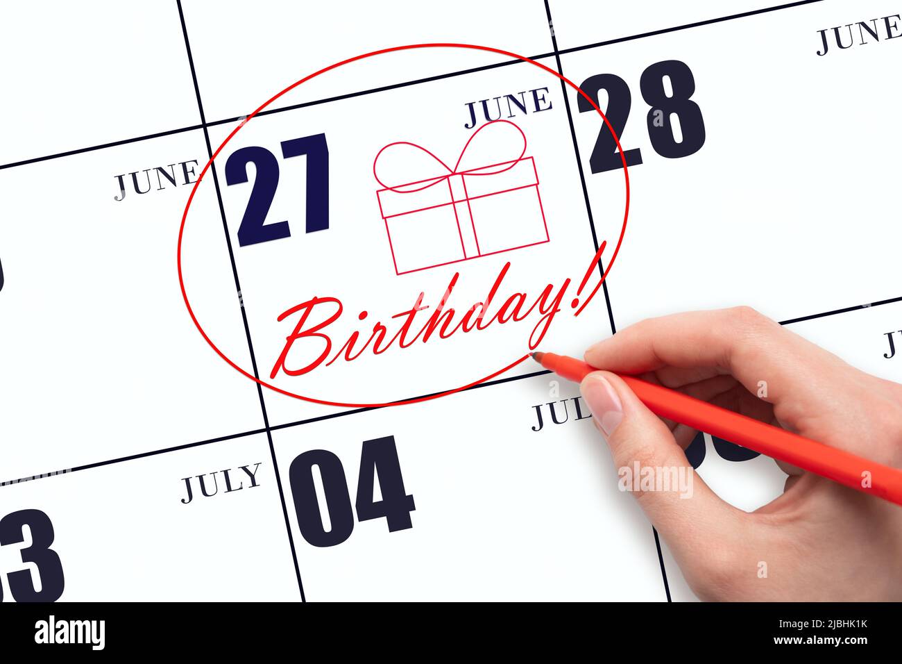 27th day of June. The hand circles the date on the calendar 27 June, draws a gift box and writes the text Birthday. Holiday. Summer month, day of the Stock Photo