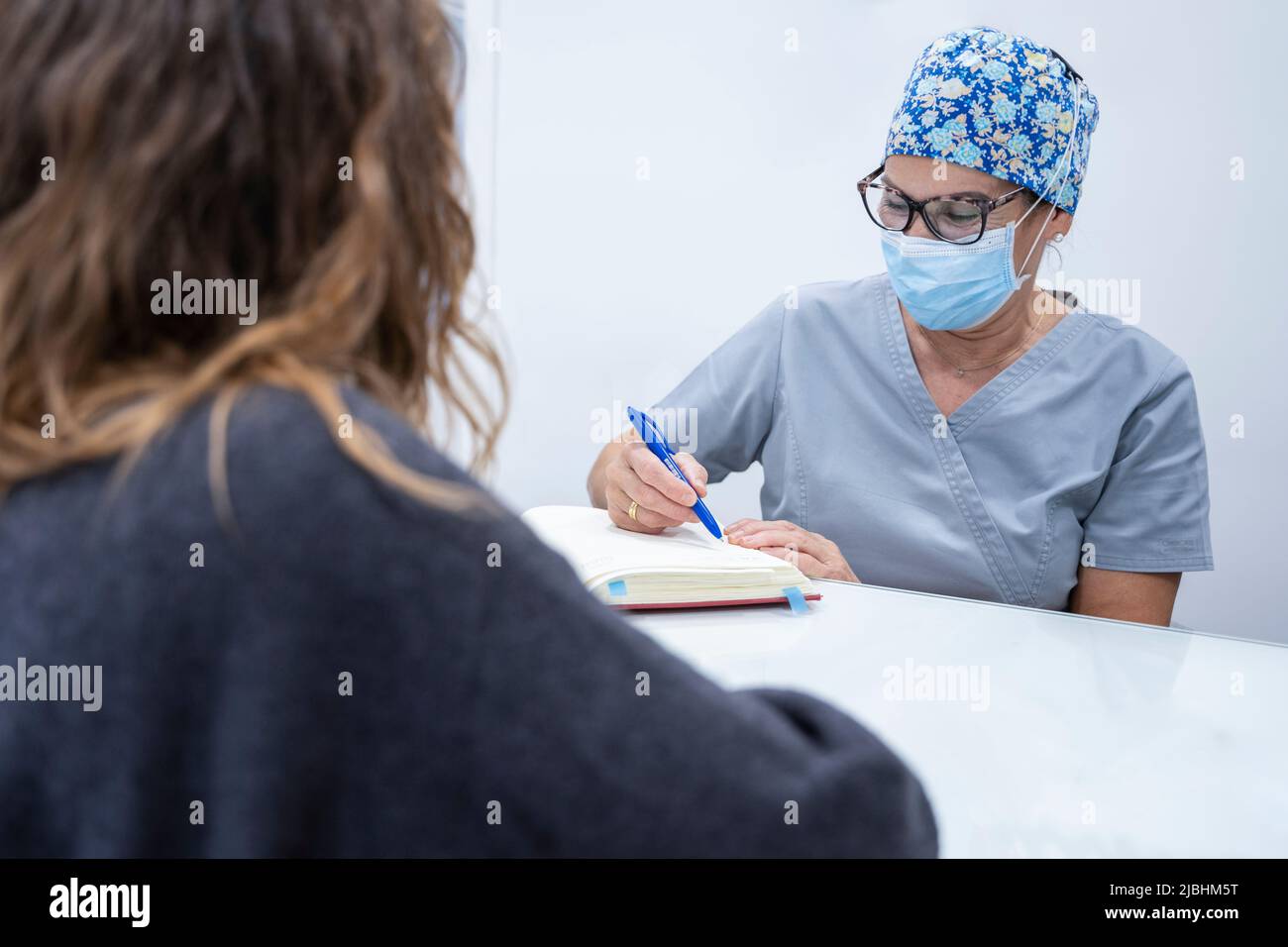 Woman assistant points out an appointment to patient in dental clinic Stock Photo