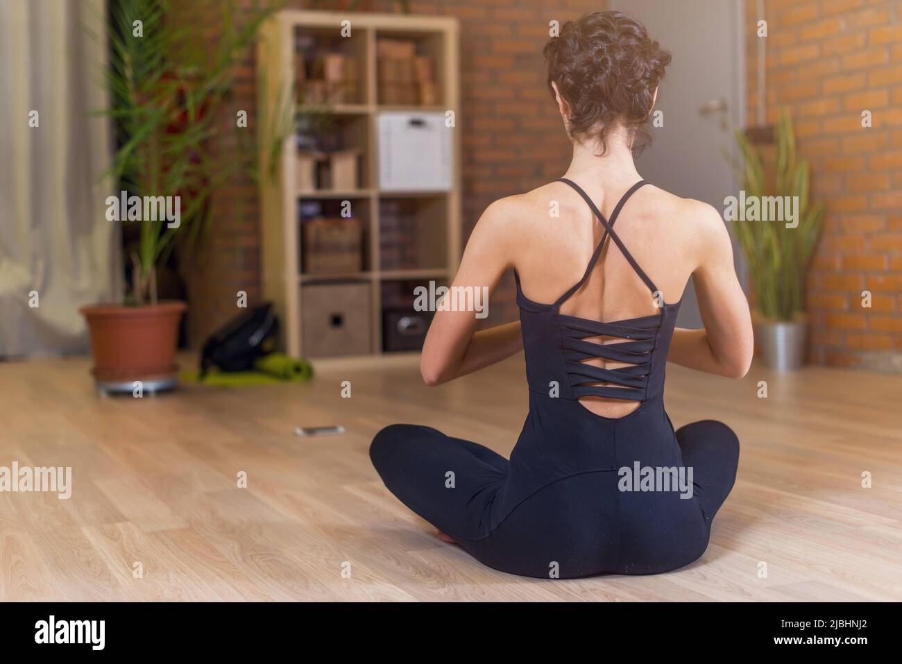 Back view of woman sitting in yoga lotus pose relaxing and meditating ...