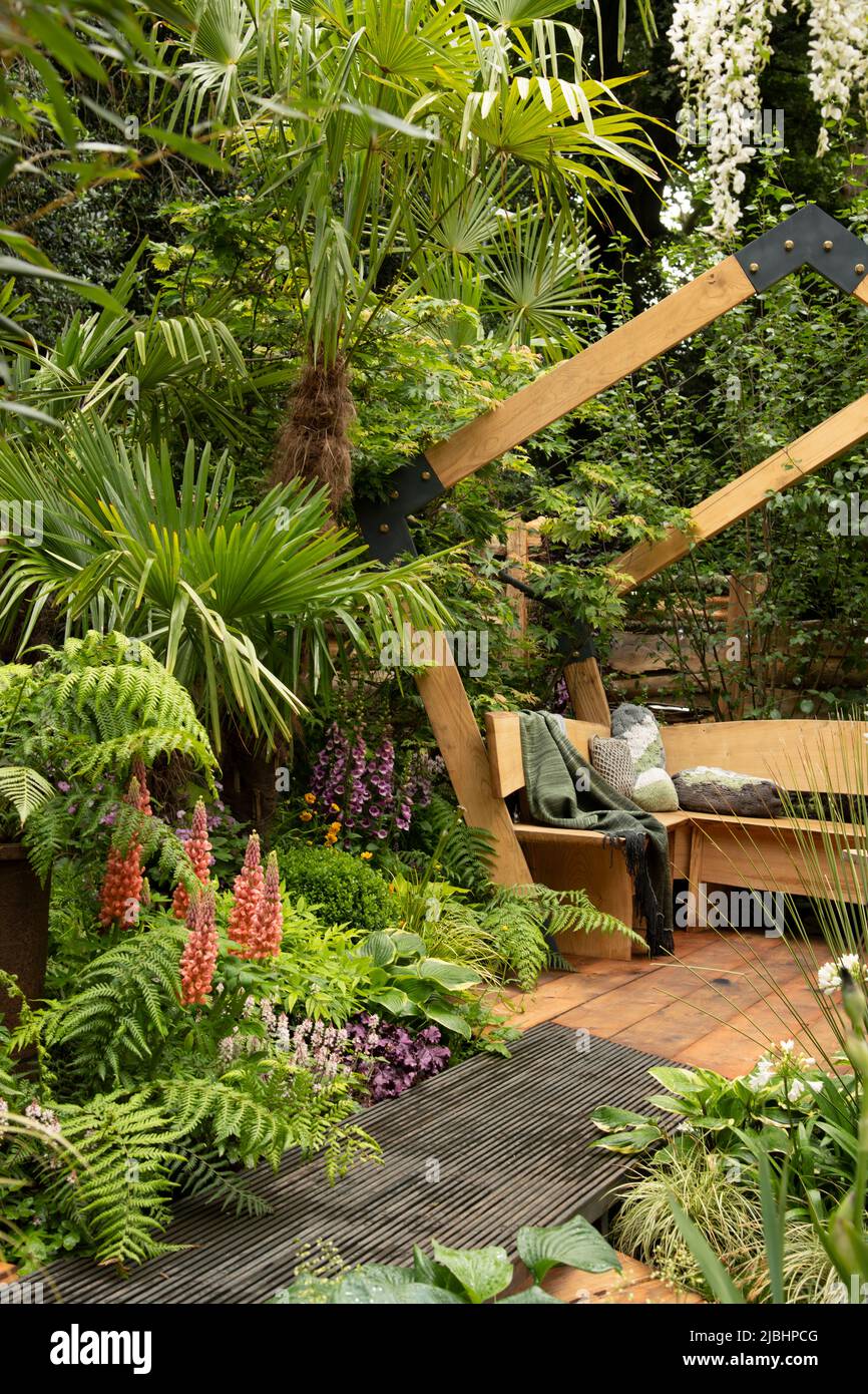 A contemporary wooden arch and daybed platform surrounded by lush planting in the  Kingston Maurward Space Within Garden designed by Michelle Brown. Stock Photo