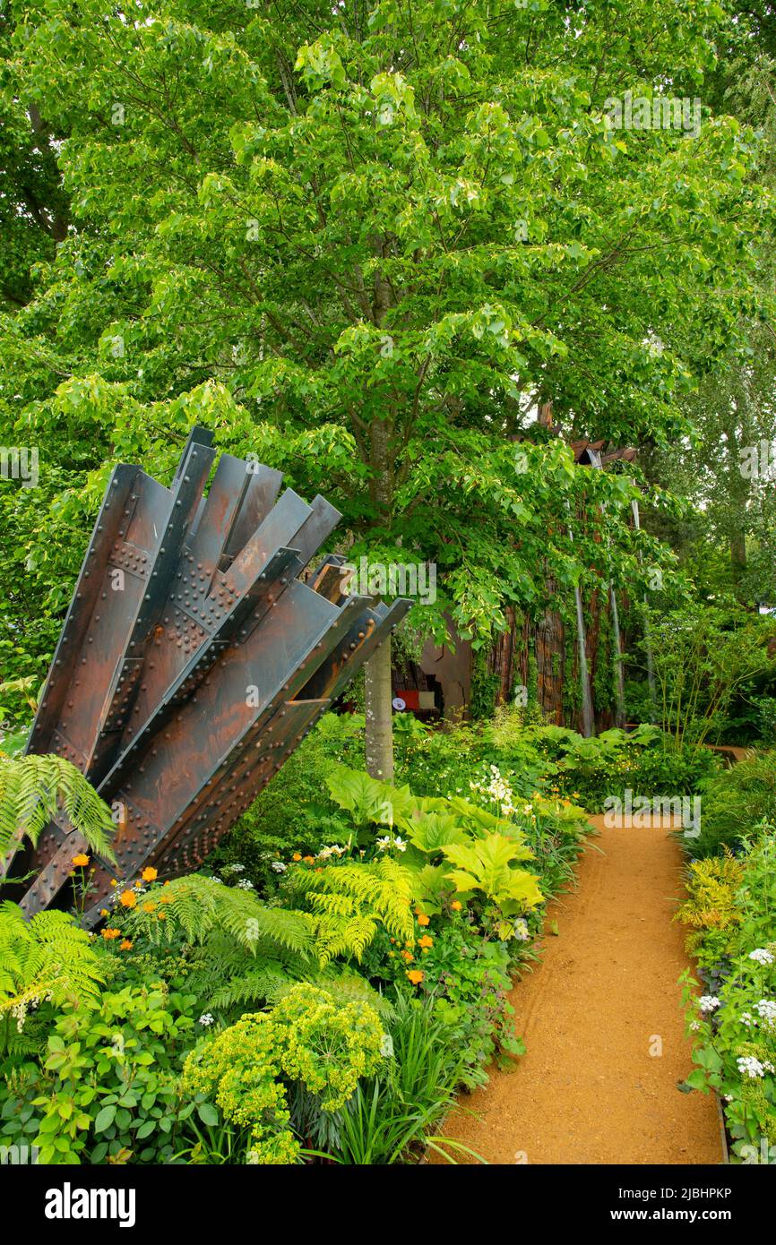 Tillia cordata ‘Greenspire’ - Small Leaved Lime above an industrial style sculpture and path through damp-loving forest planting in the Medire Smartpl Stock Photo